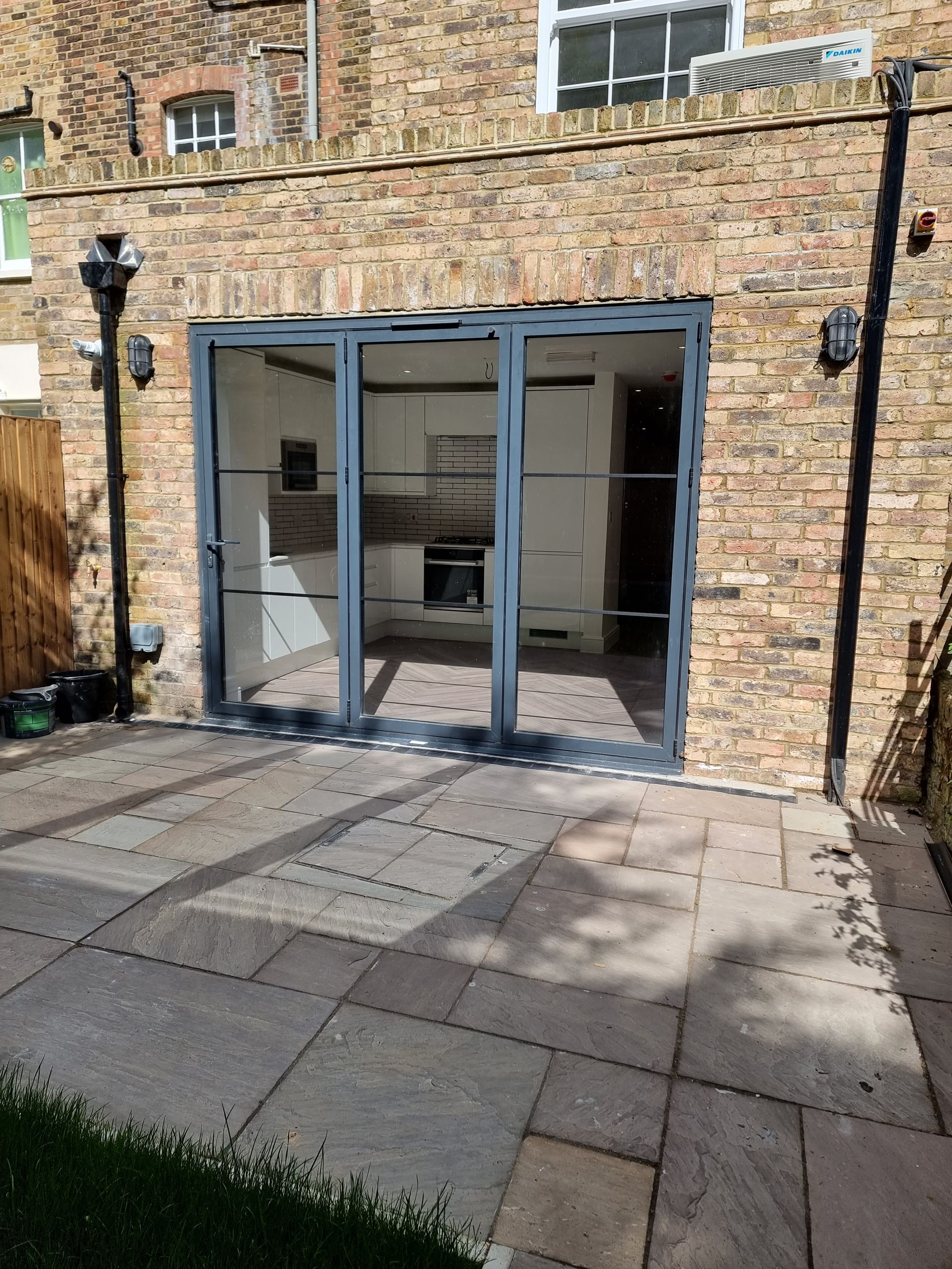 Exterior view of a brick building with large glass doors opening to a stone patio.
