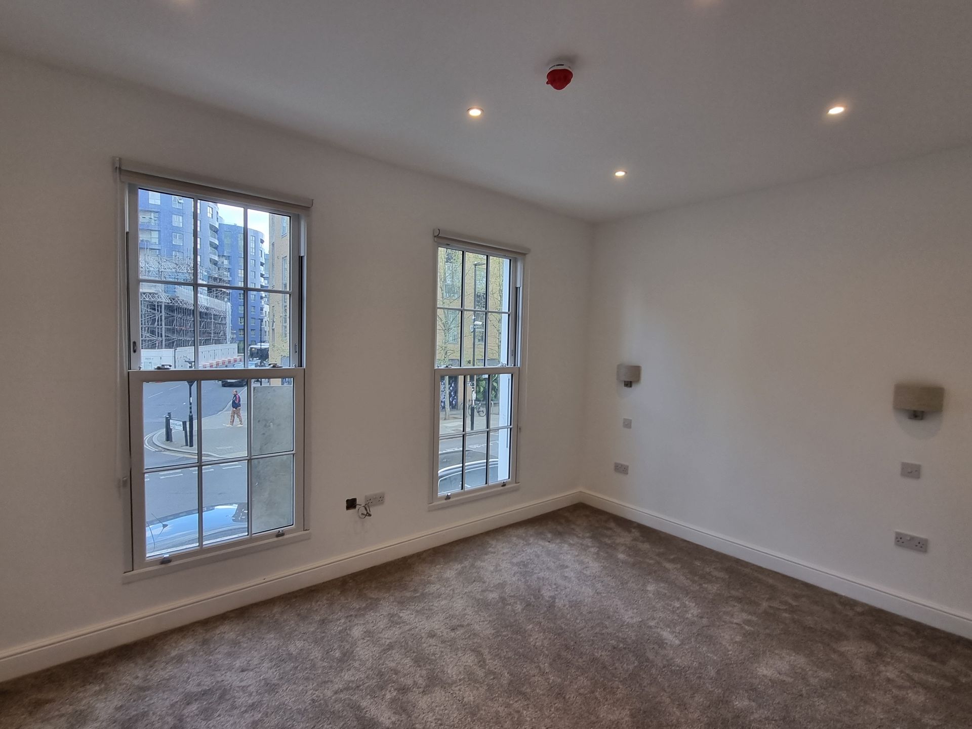 Empty room with two tall windows, neutral walls, and a carpeted floor.