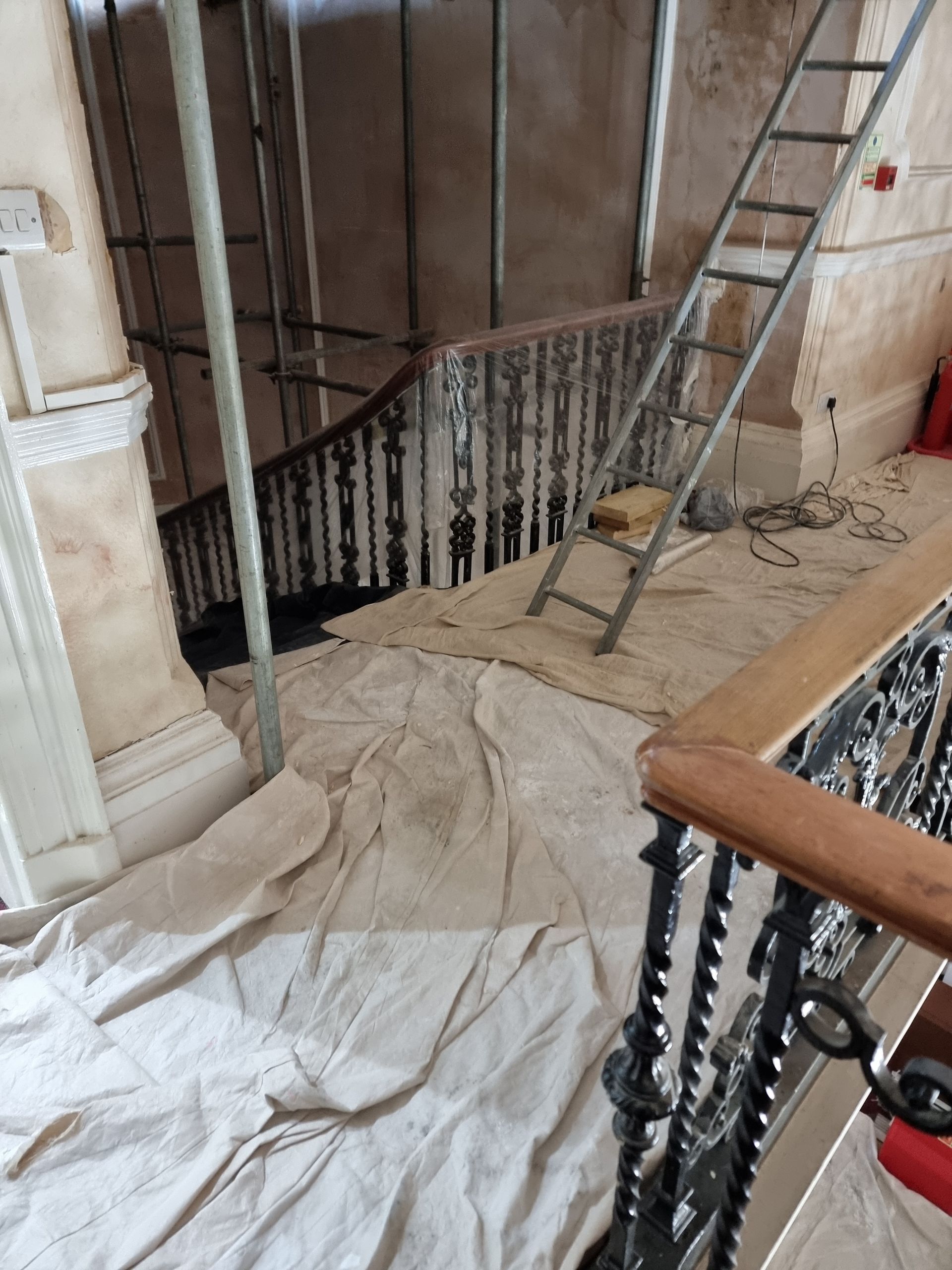 A staircase with a ladder and a white cloth on the floor.