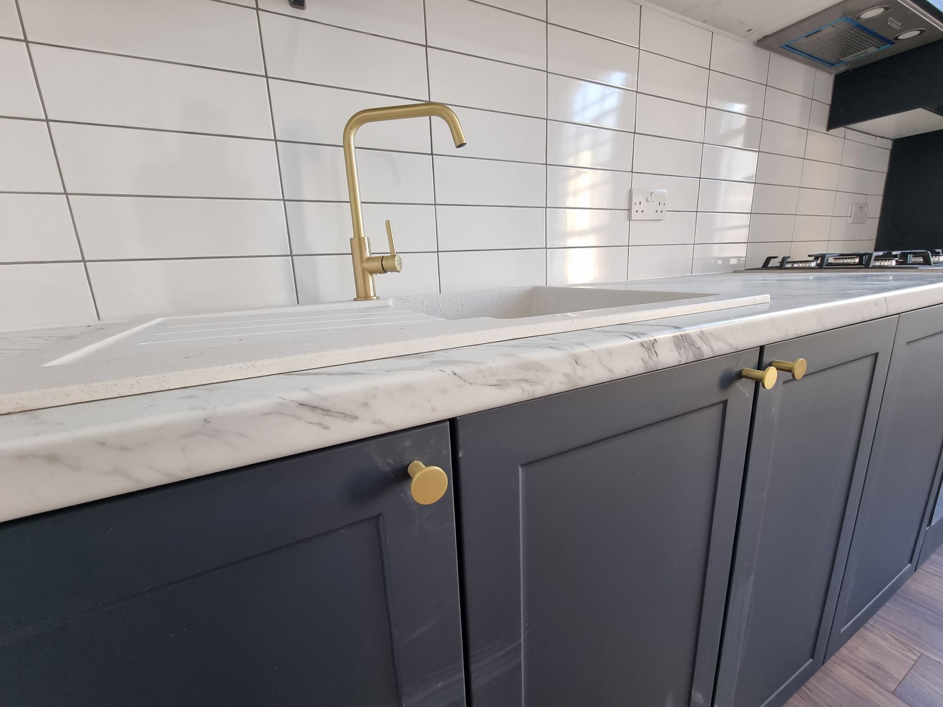 A kitchen with a sink and a brass faucet