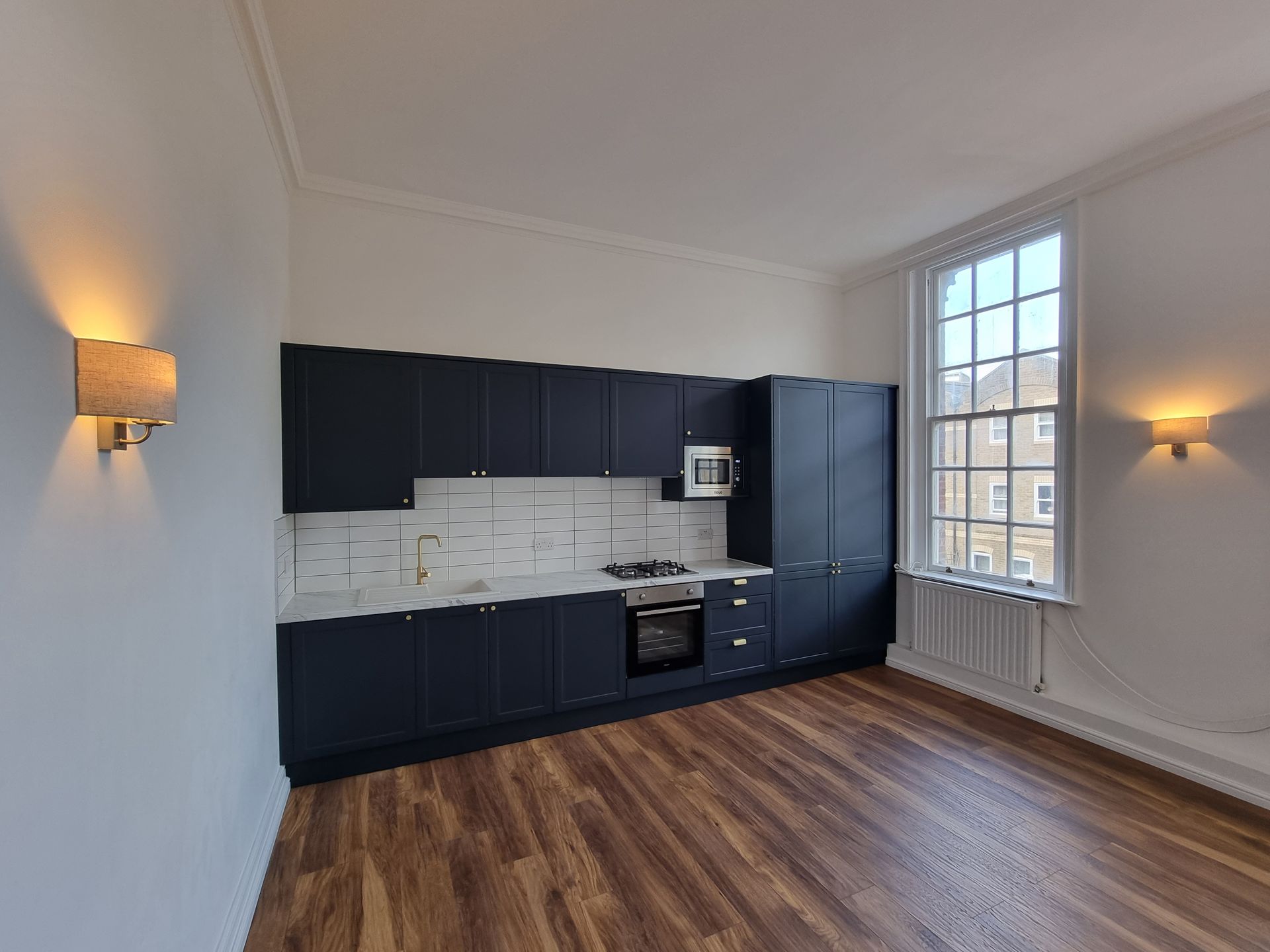 A kitchen with black cabinets and a wooden floor
