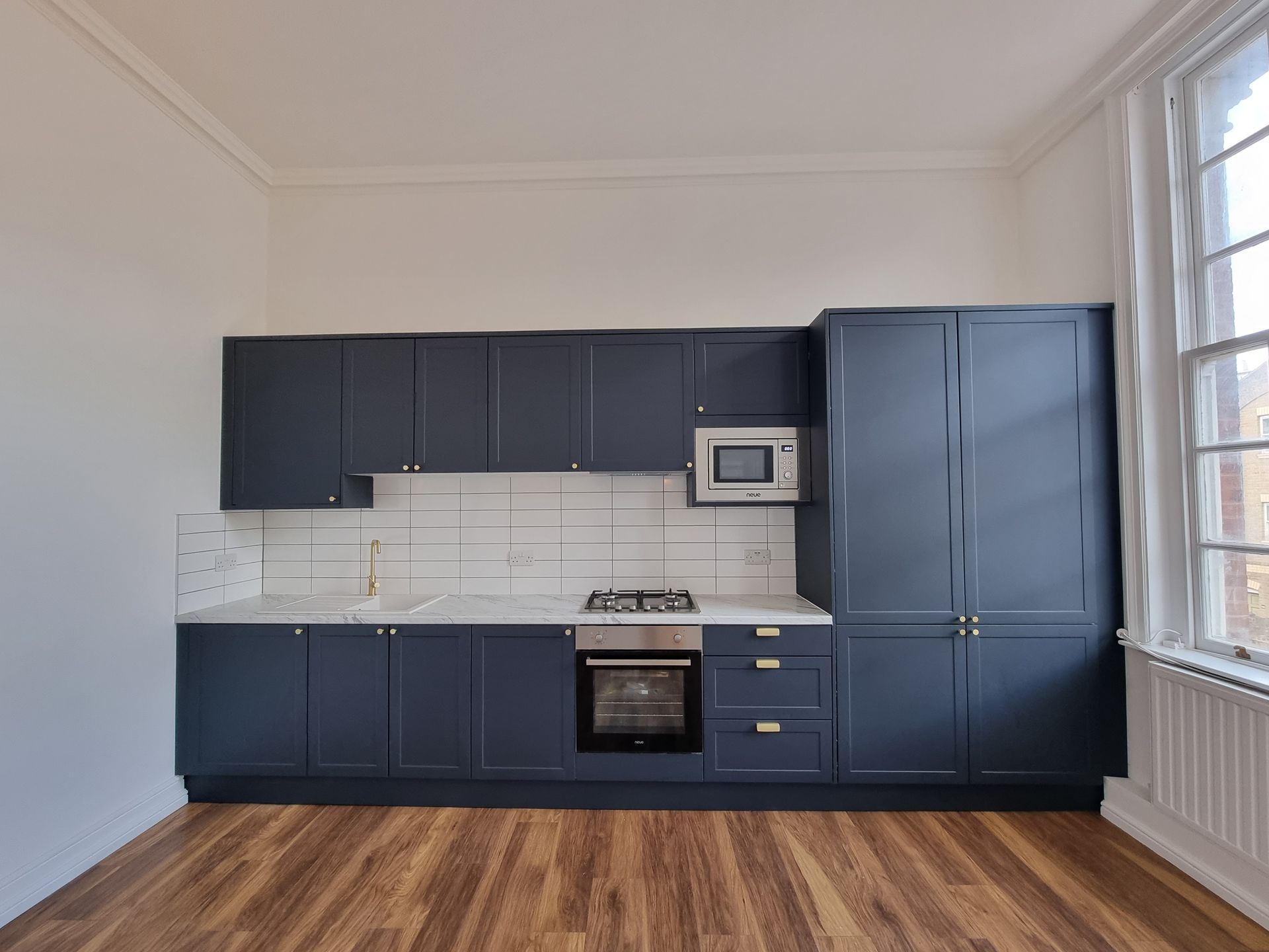 An empty kitchen with blue cabinets and a microwave