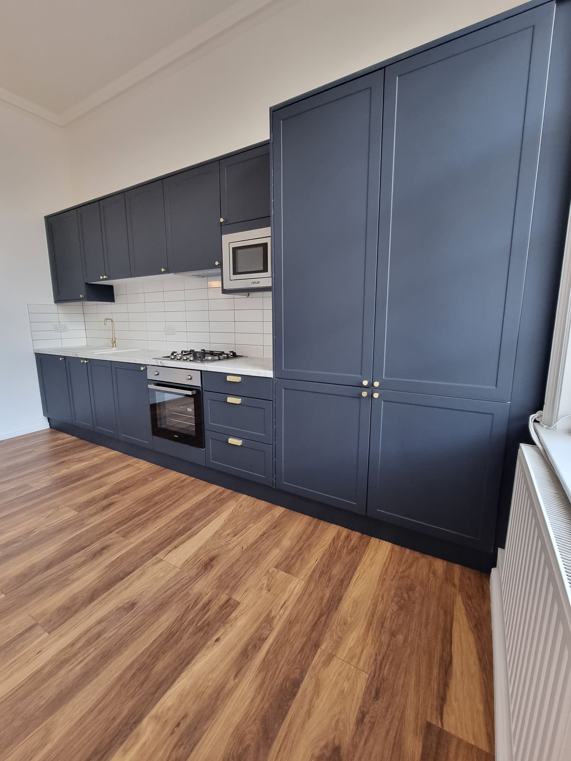 A kitchen with black cabinets and a wooden floor.