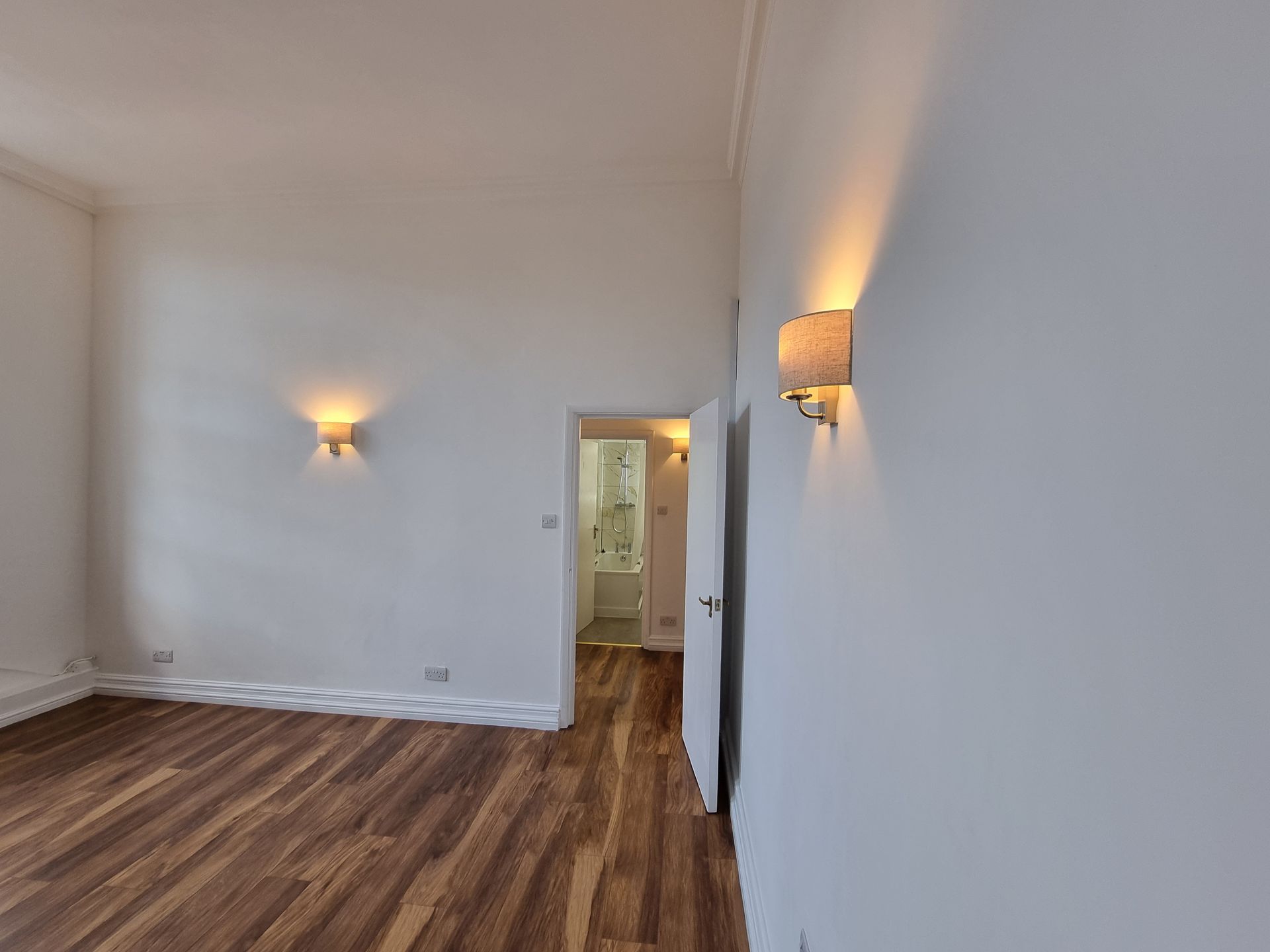 An empty room with hardwood floors and white walls