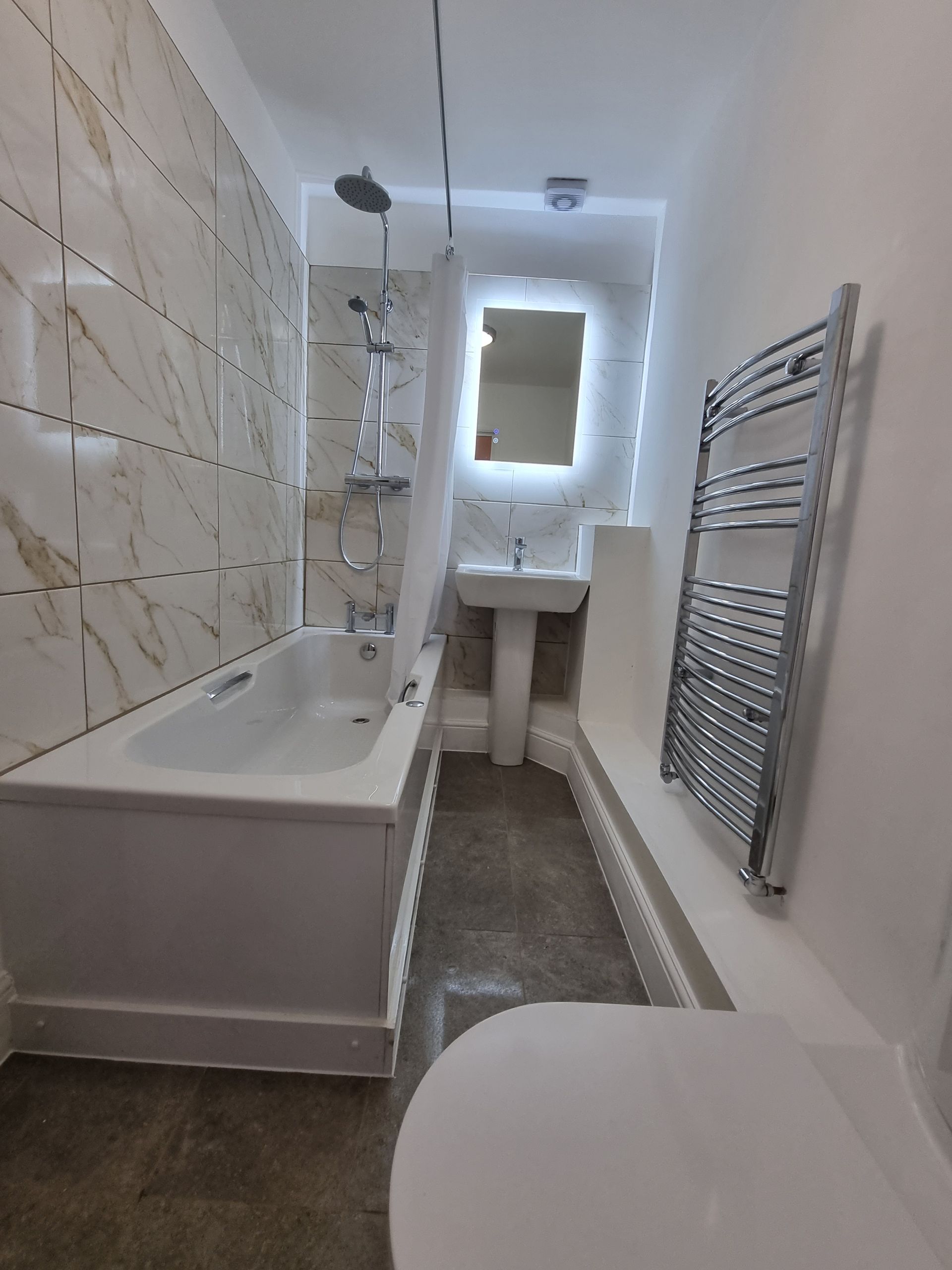 A bathroom with a bathtub , sink , toilet and mirror.