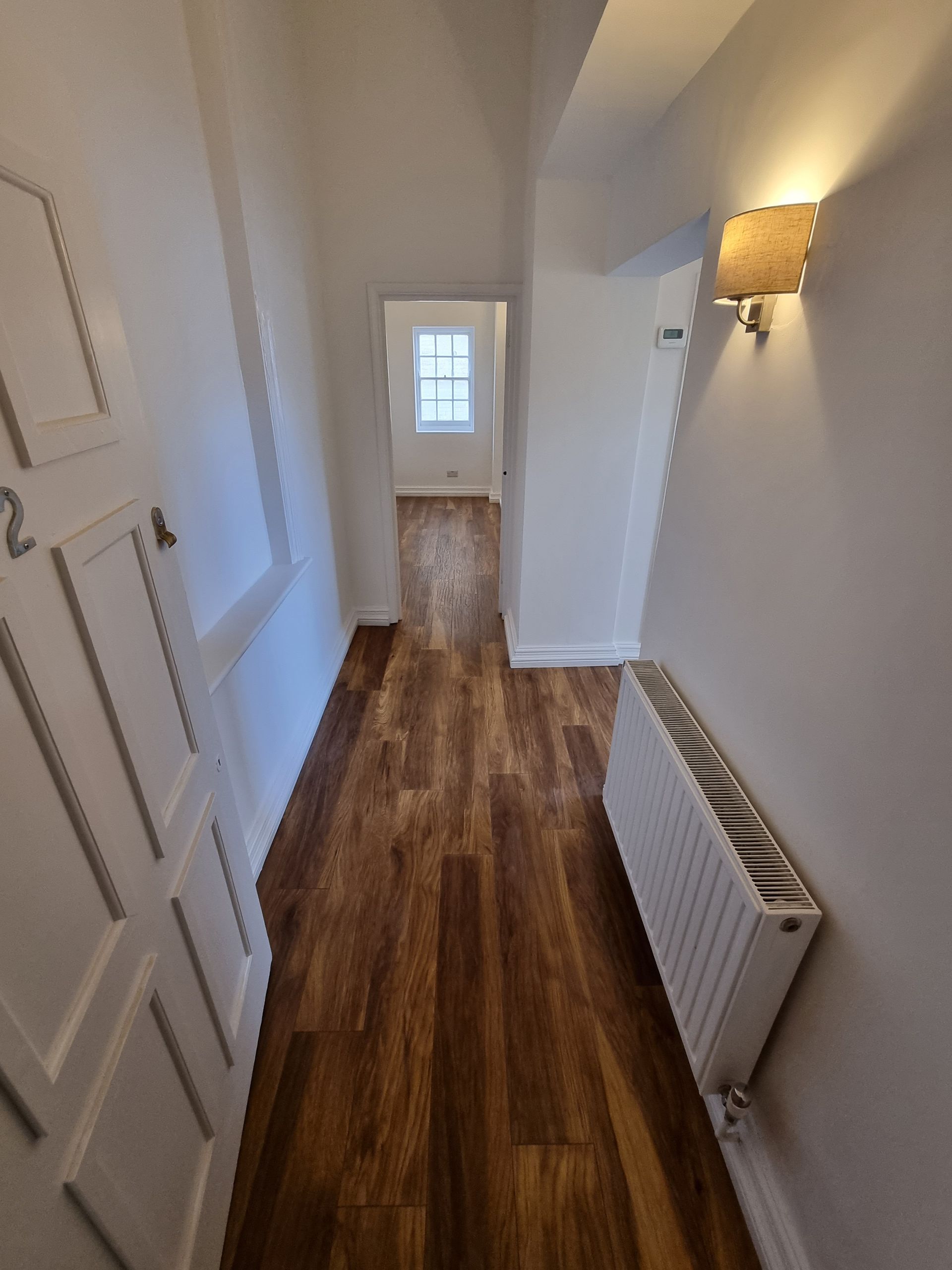 A hallway with wooden floors and a radiator