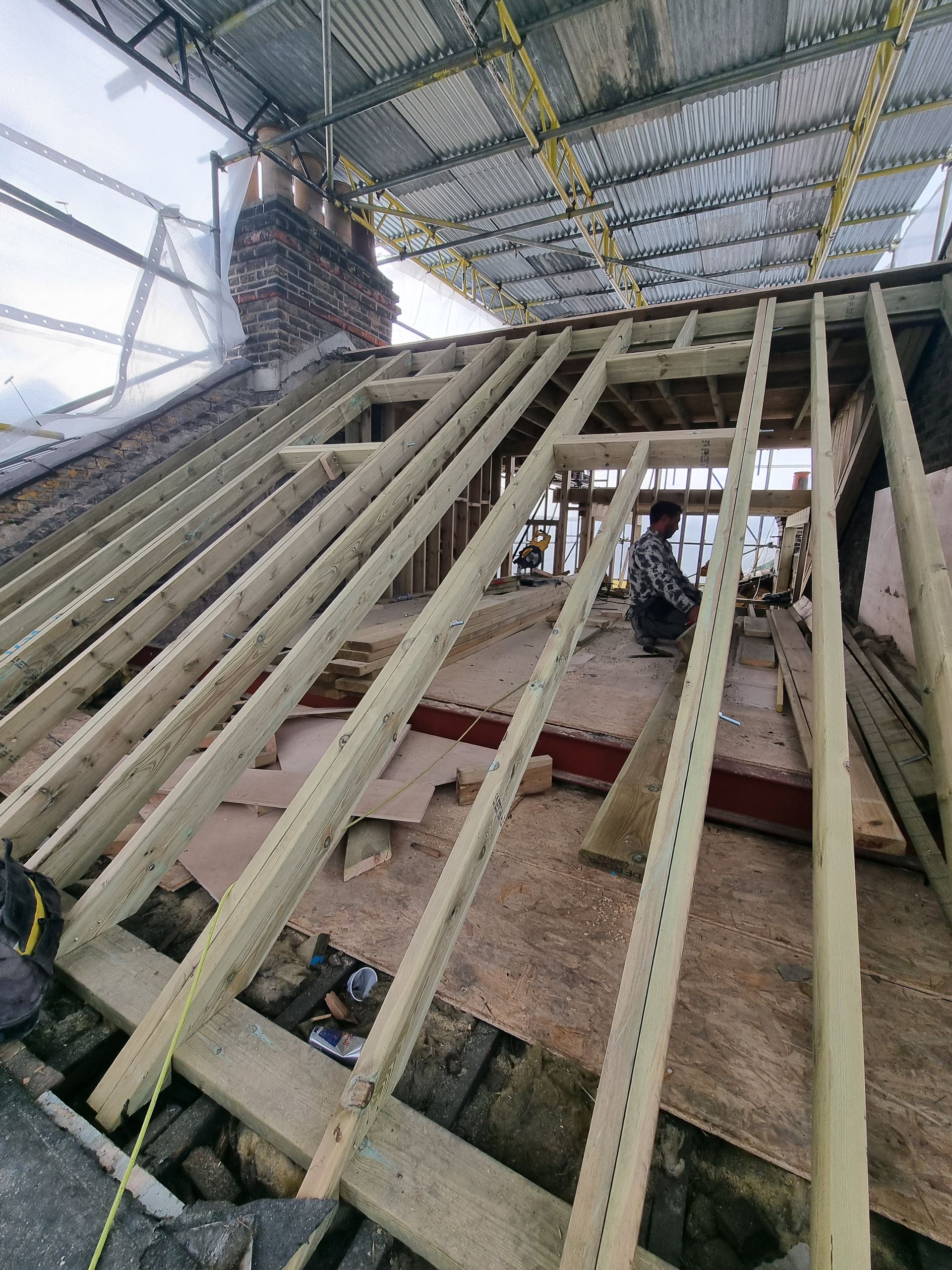 A roof is being built with wooden beams and a chimney.