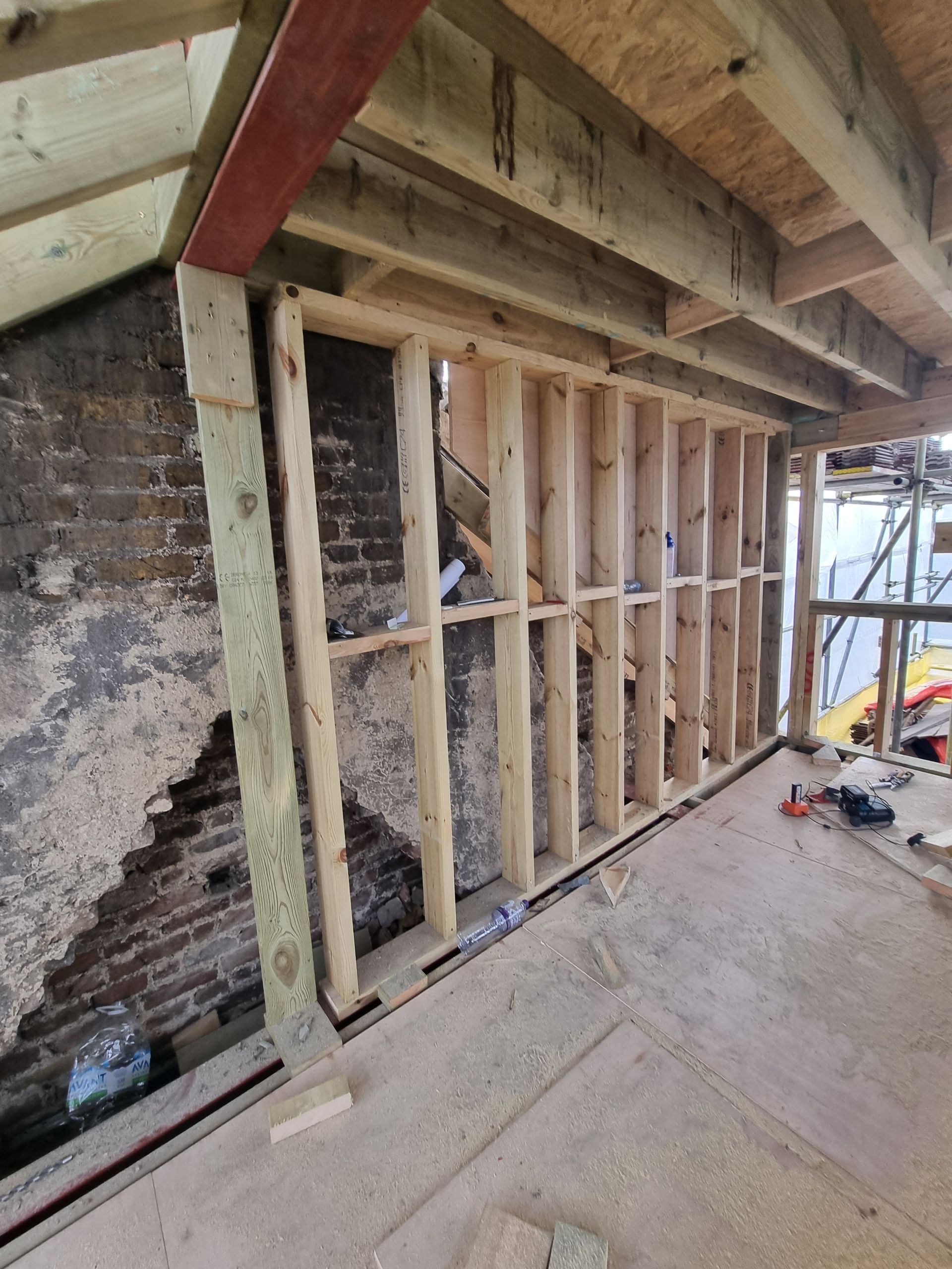 A wooden frame is being built around a brick wall.