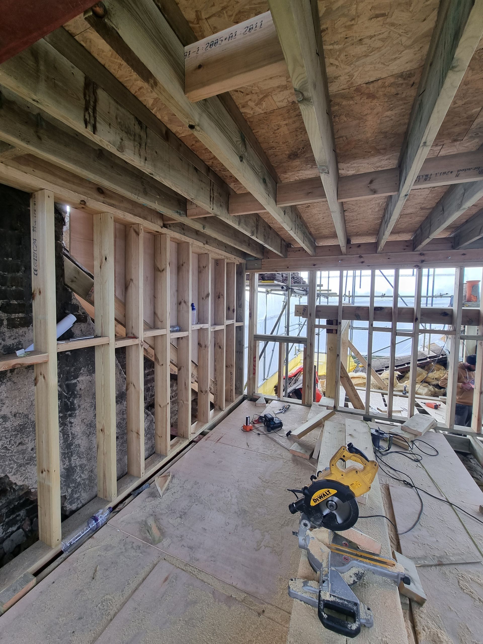A room under construction with a circular saw on the floor.