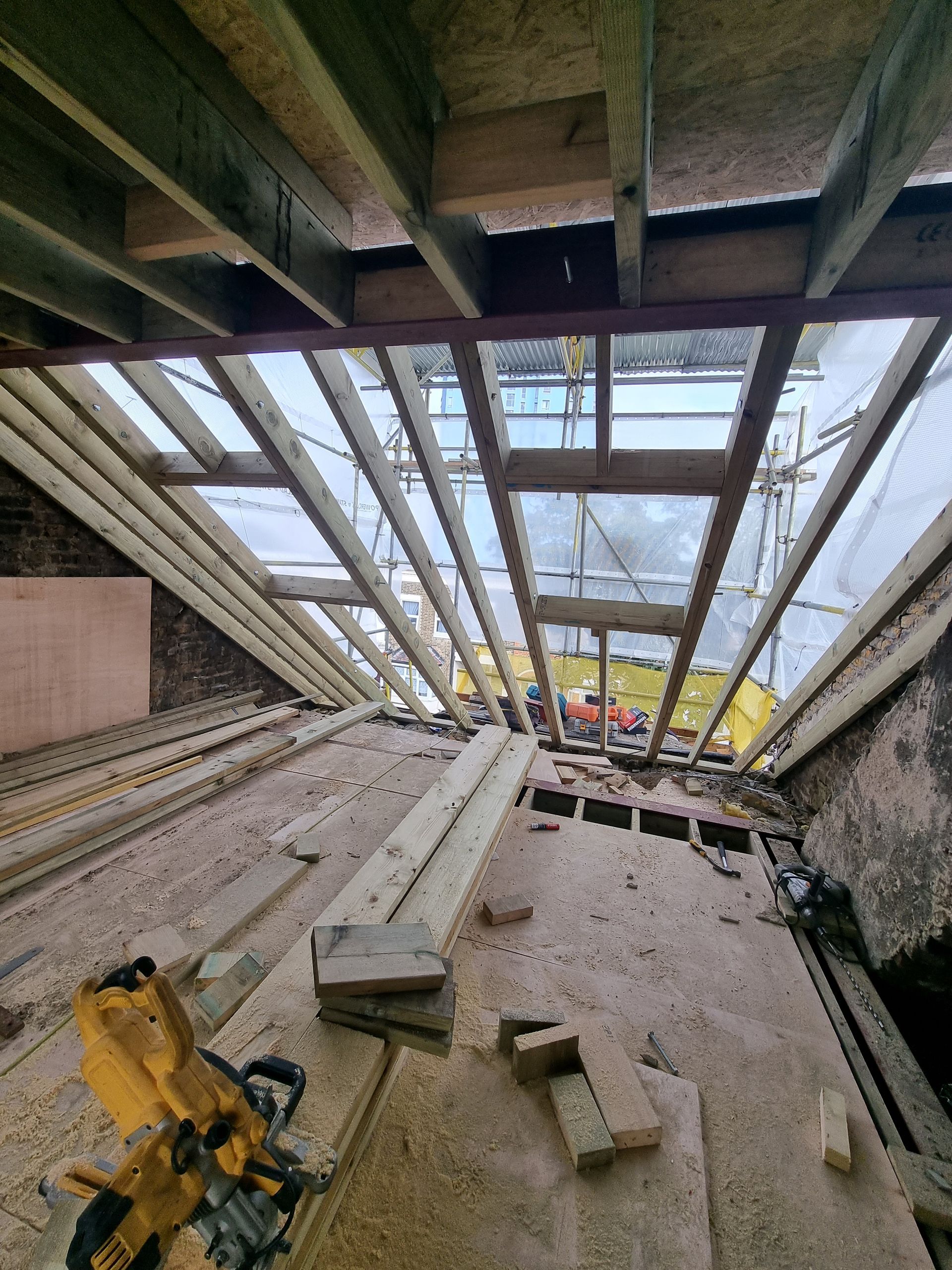 A construction site with a lot of wood and a saw.