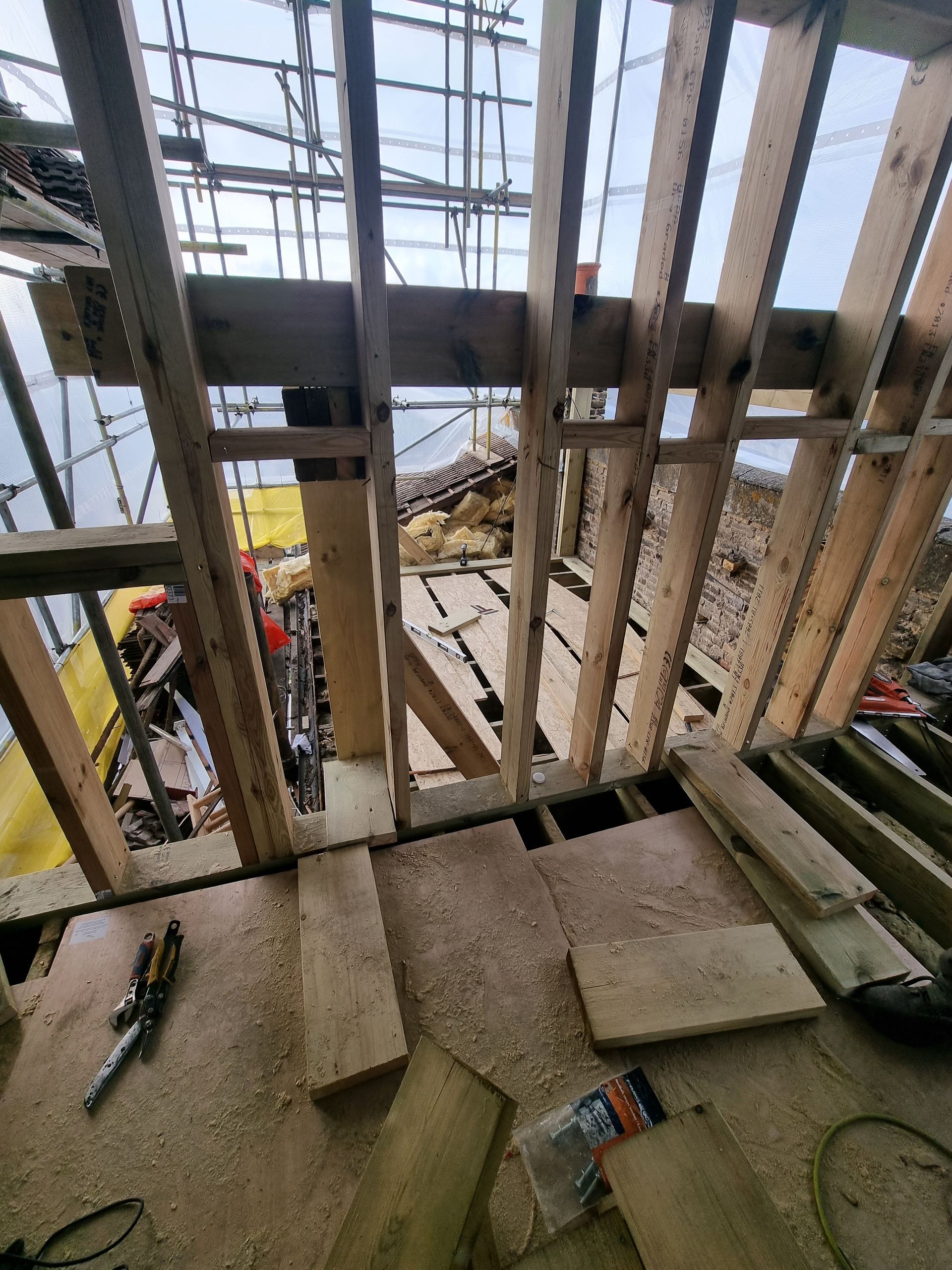 The inside of a building under construction with wooden beams and scaffolding.