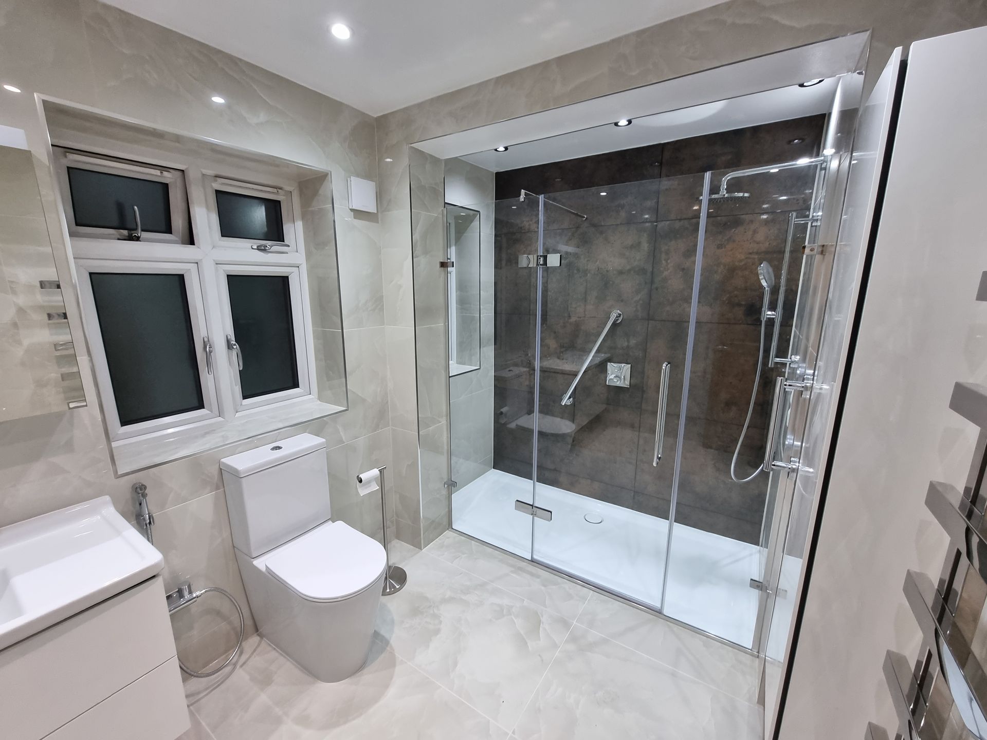 A bathroom with a toilet , sink , shower and window.