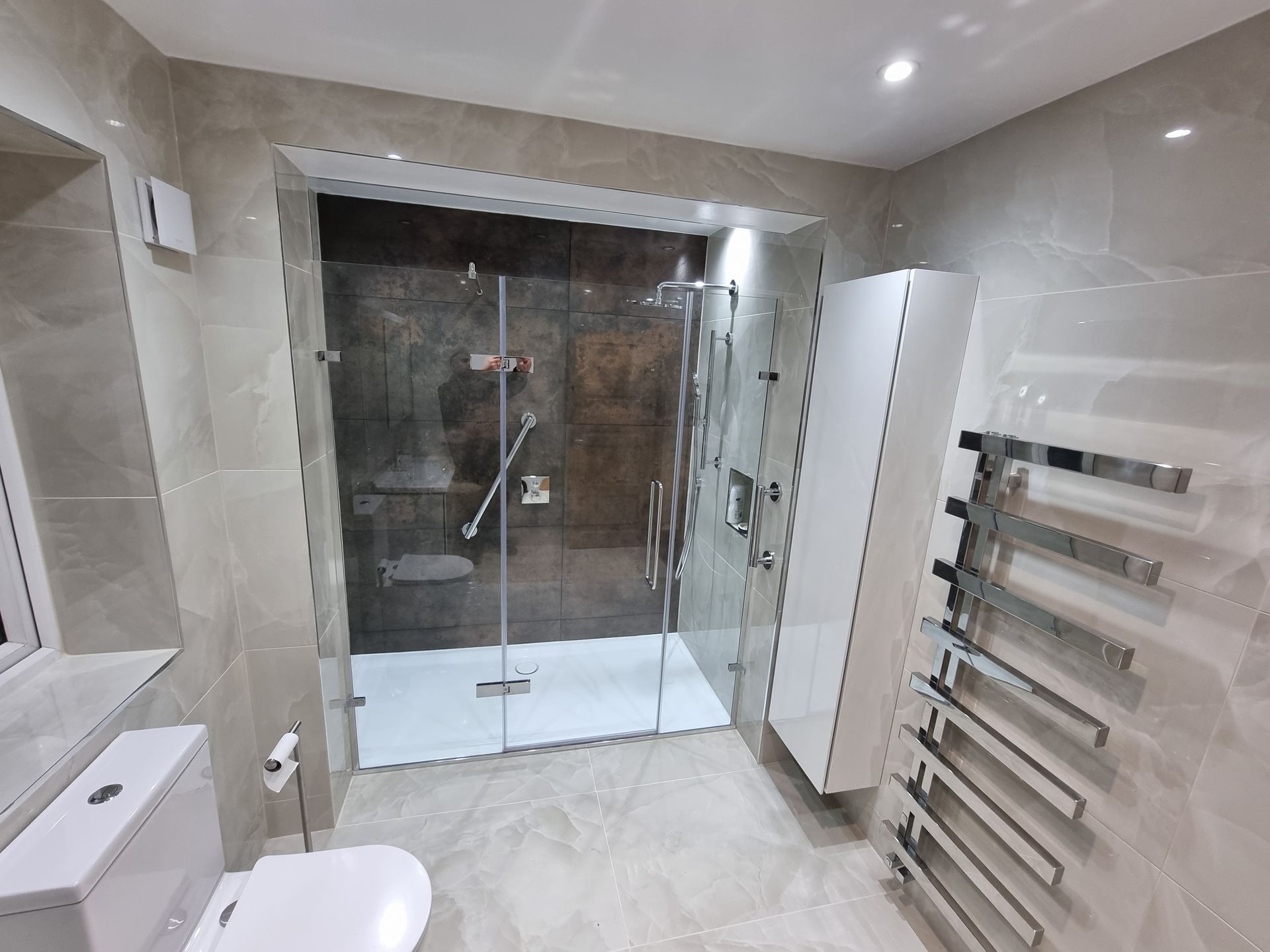 Modern bathroom with glass shower, white cabinet, and towel rack.