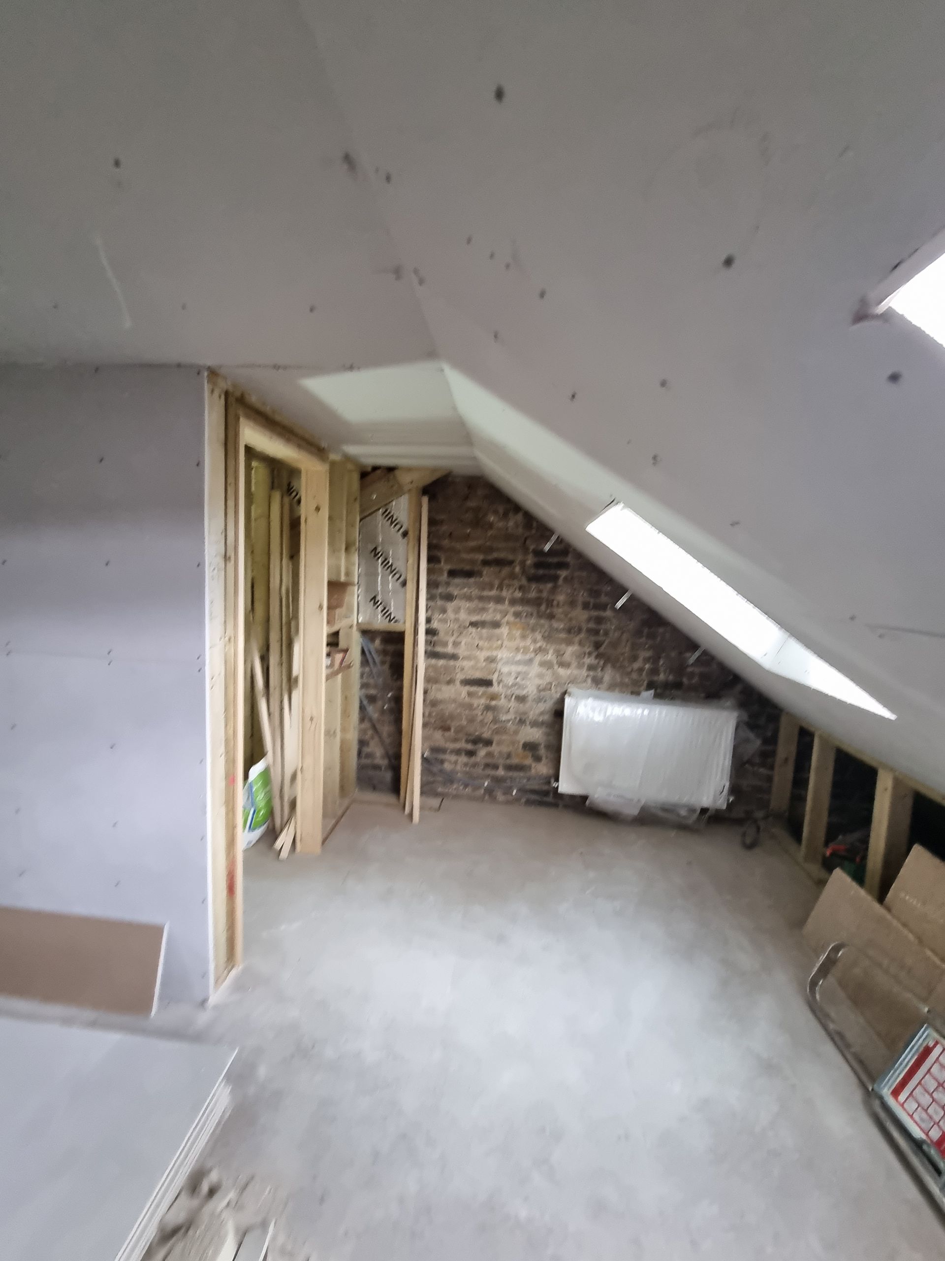 An empty attic with a brick wall and a skylight