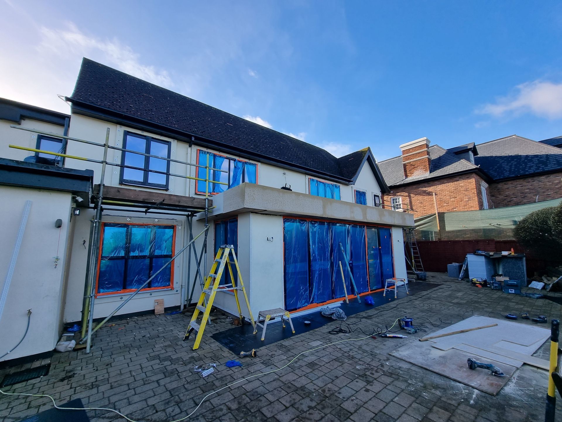 A large house is being built with a ladder in front of it.