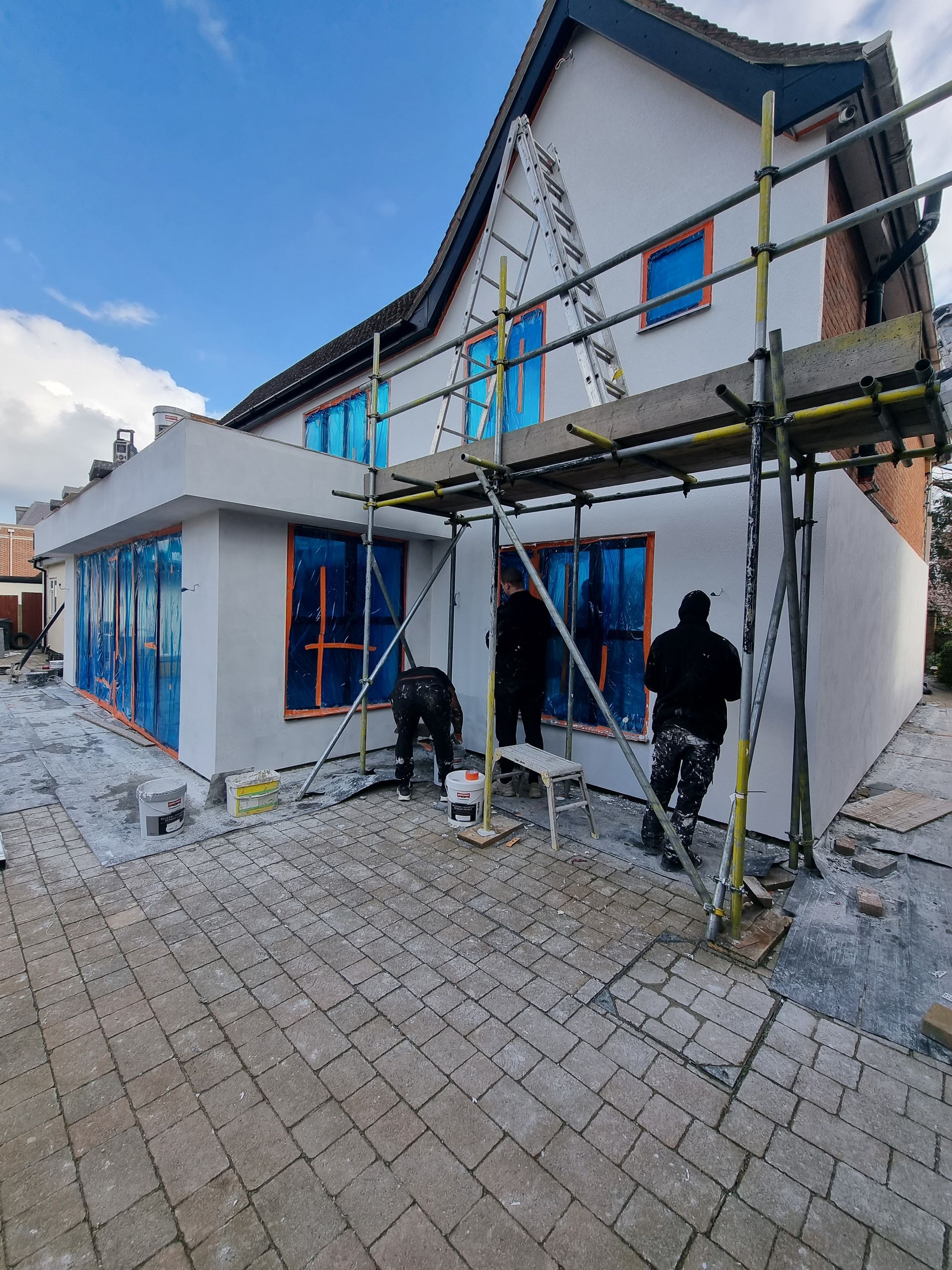 A group of people are working on a house with scaffolding around it.