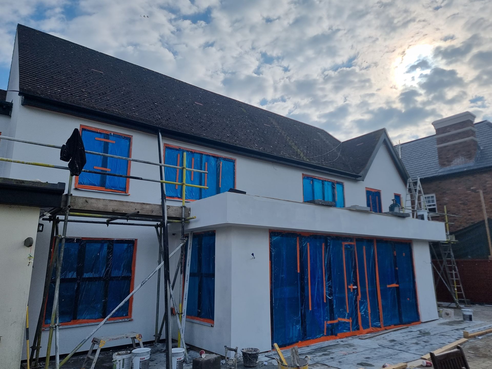 A white house is being built with blue tarps on the windows.