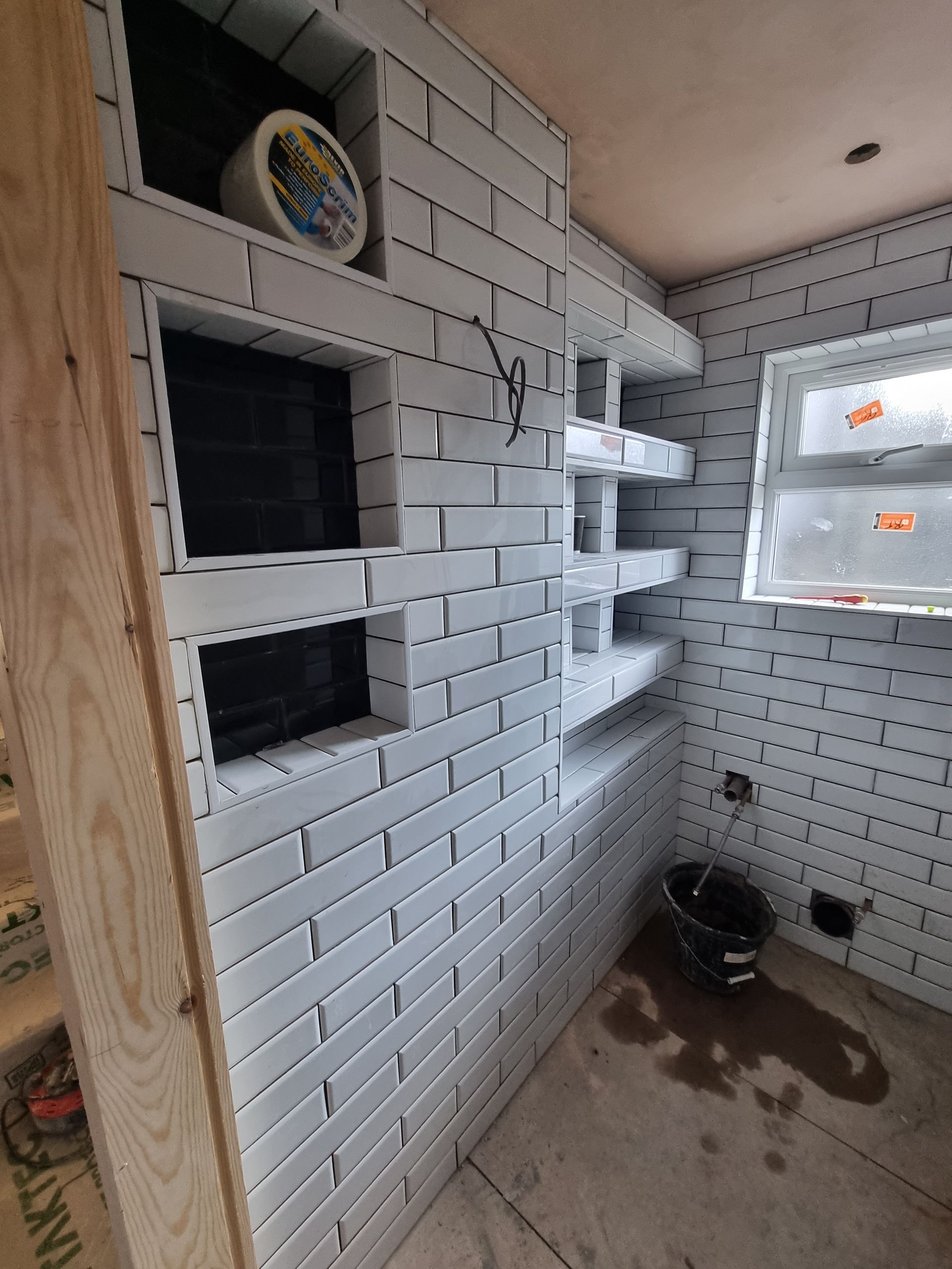 A bathroom with white brick walls and shelves.