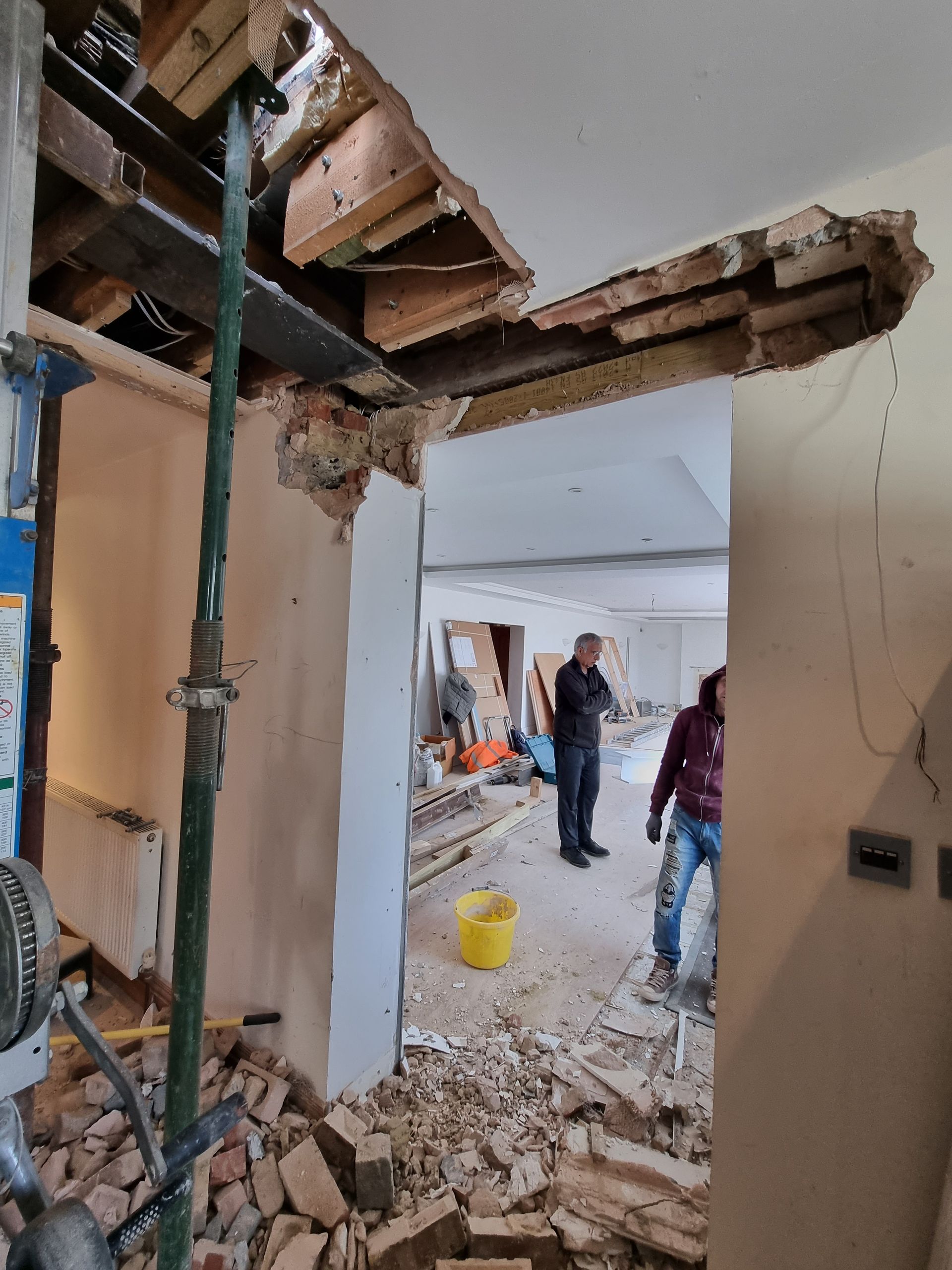 A man is standing in a room with a hole in the ceiling.