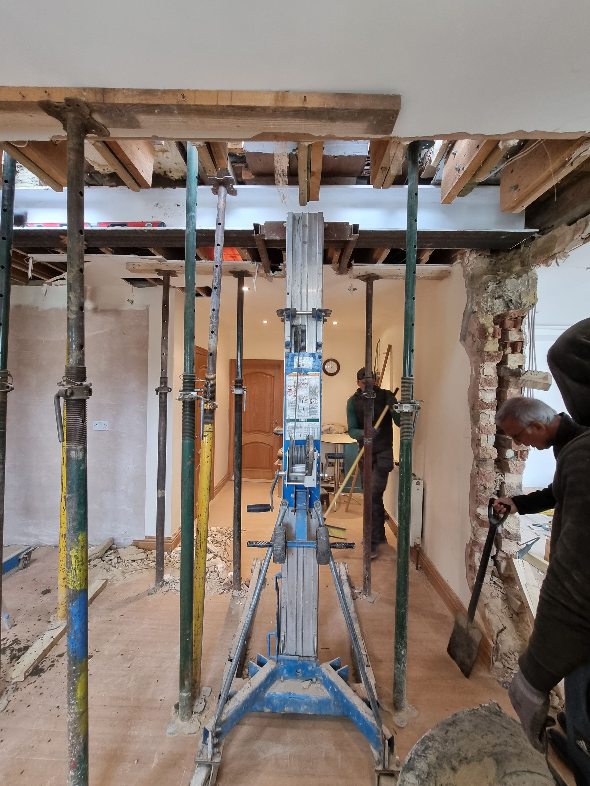 A man is standing in a room with scaffolding and a shovel.