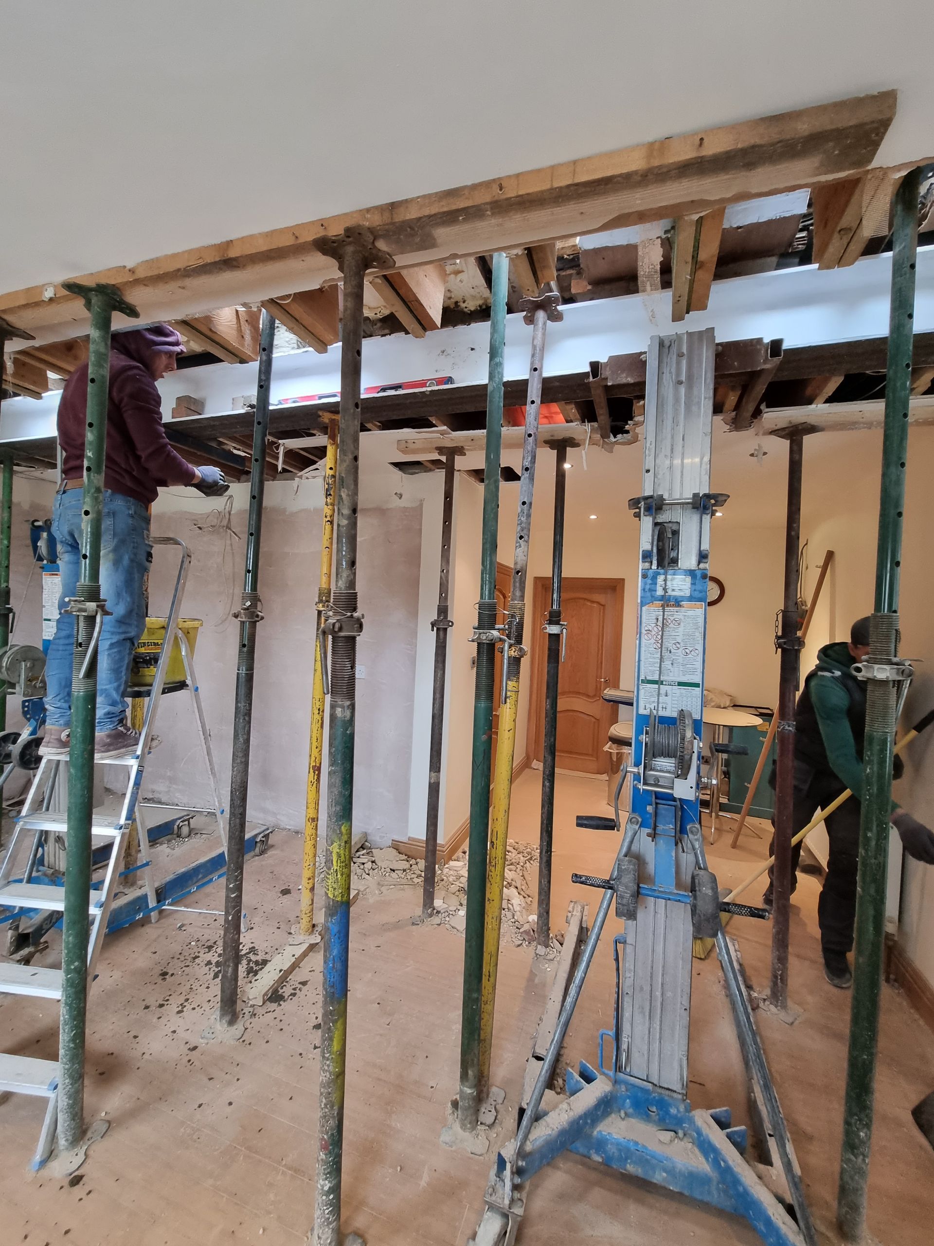 A man is standing on a ladder in a room surrounded by scaffolding.