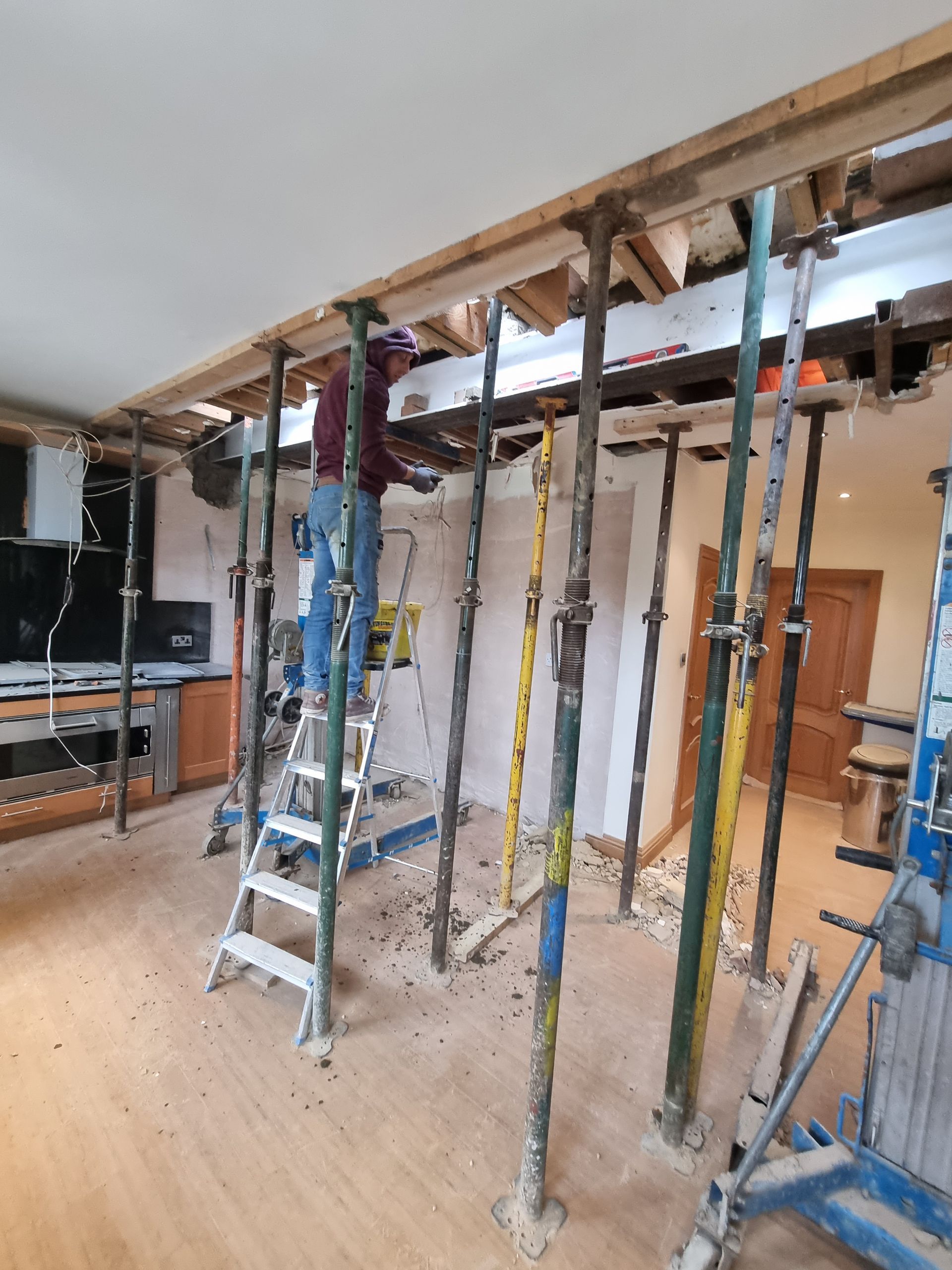 A man is standing on a ladder in a room surrounded by scaffolding.