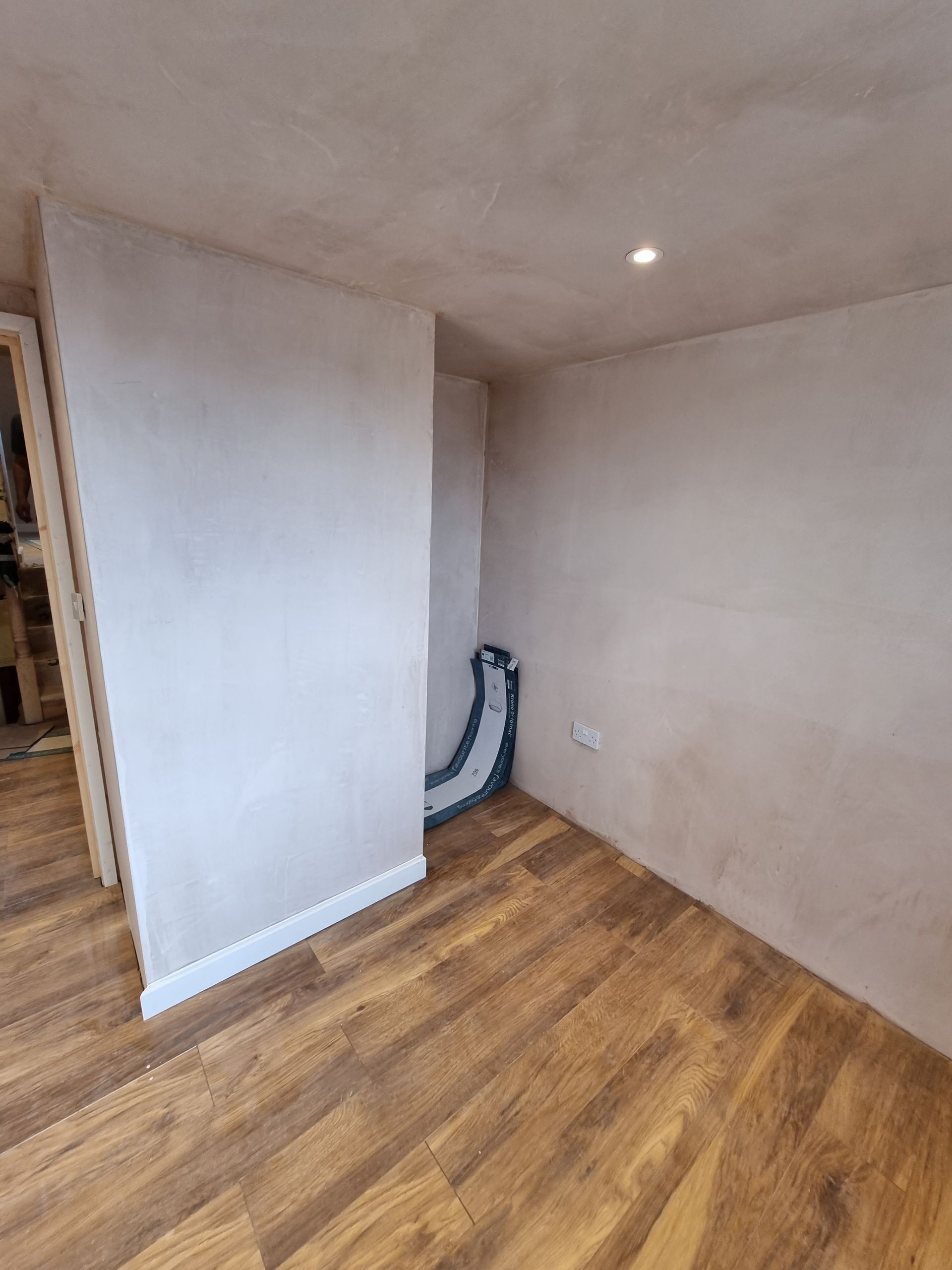 A room with a wooden floor and a white wall.