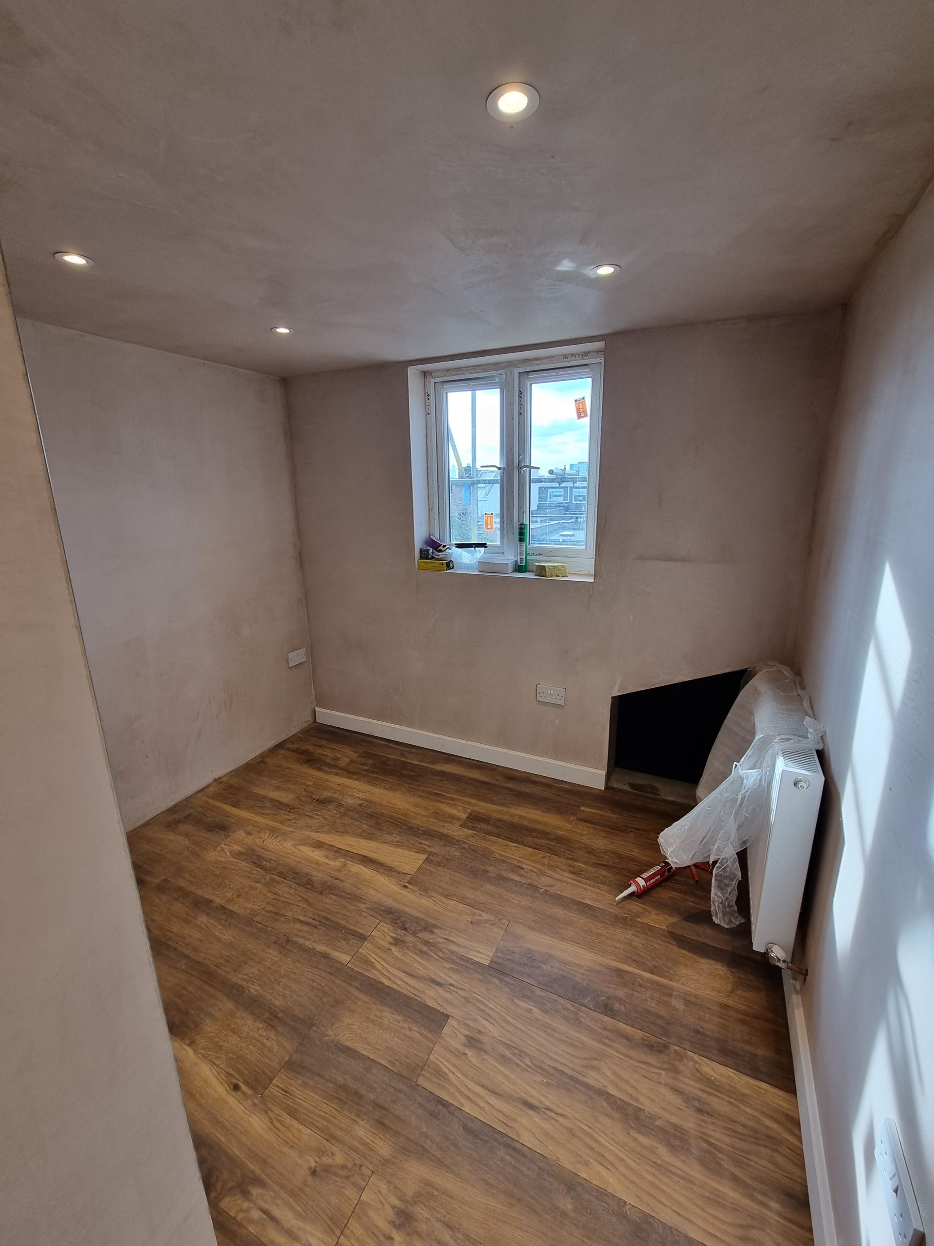 An empty room with wooden floors and a window.