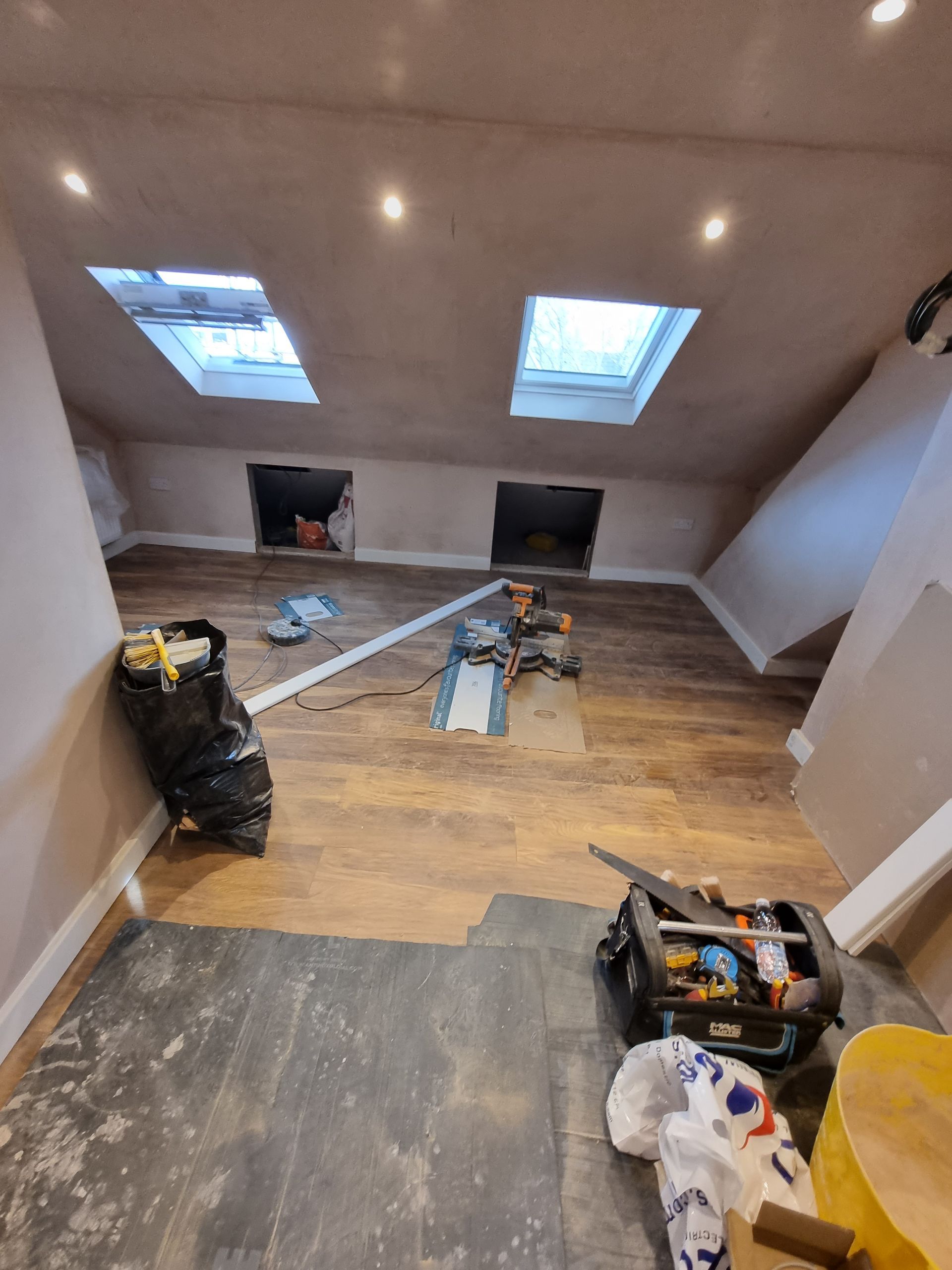 A room with a wooden floor and two skylights on the ceiling.
