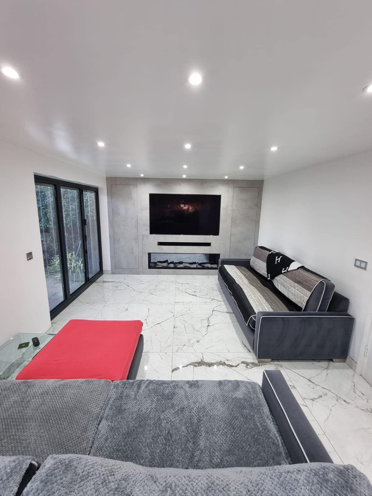 A living room with a couch , ottoman , television and fireplace.