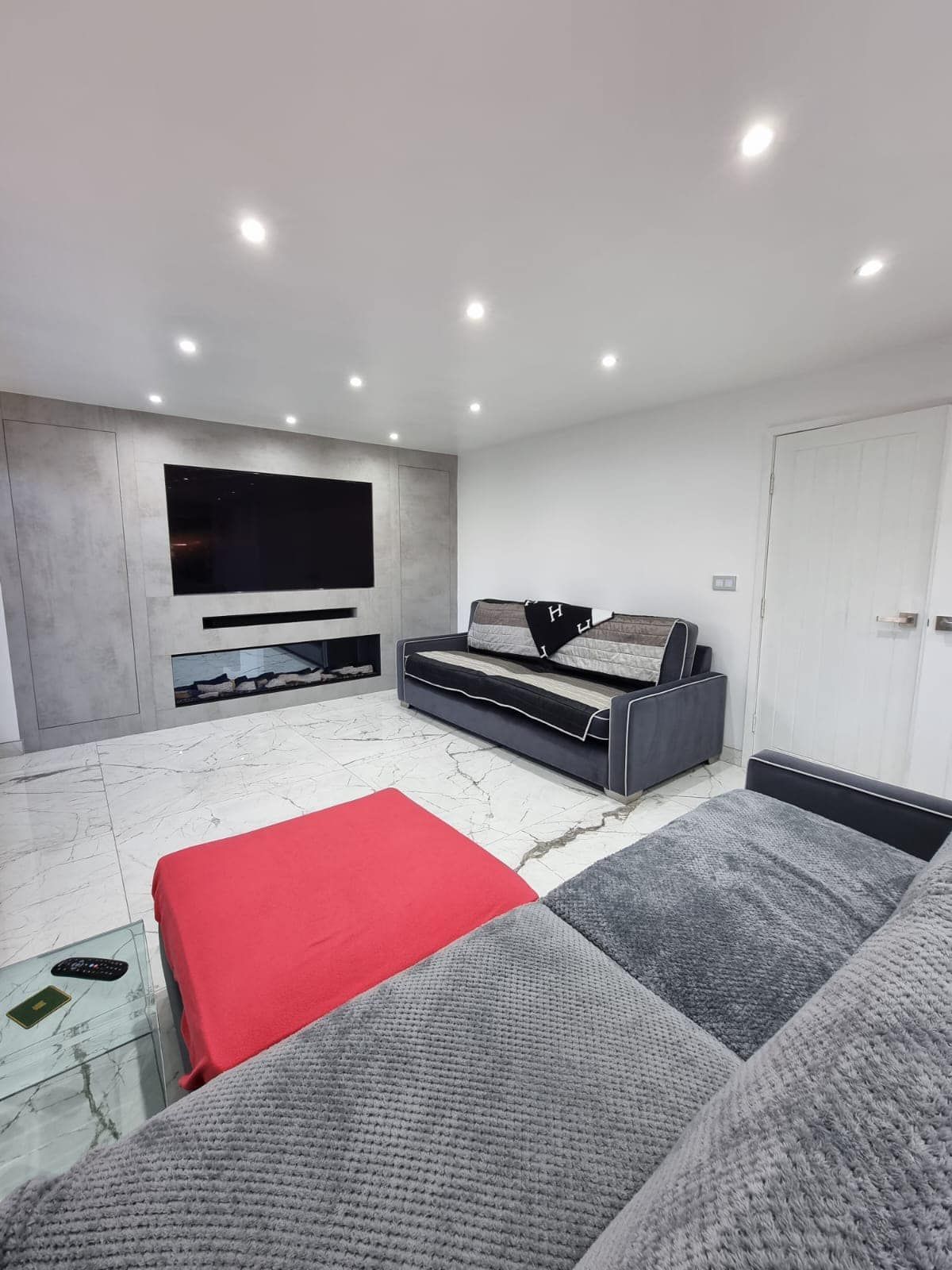 A living room with a couch , ottoman , and television.