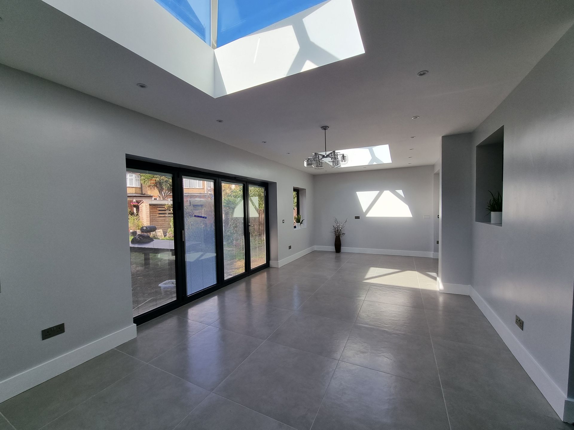 A large empty room with a skylight and sliding glass doors.