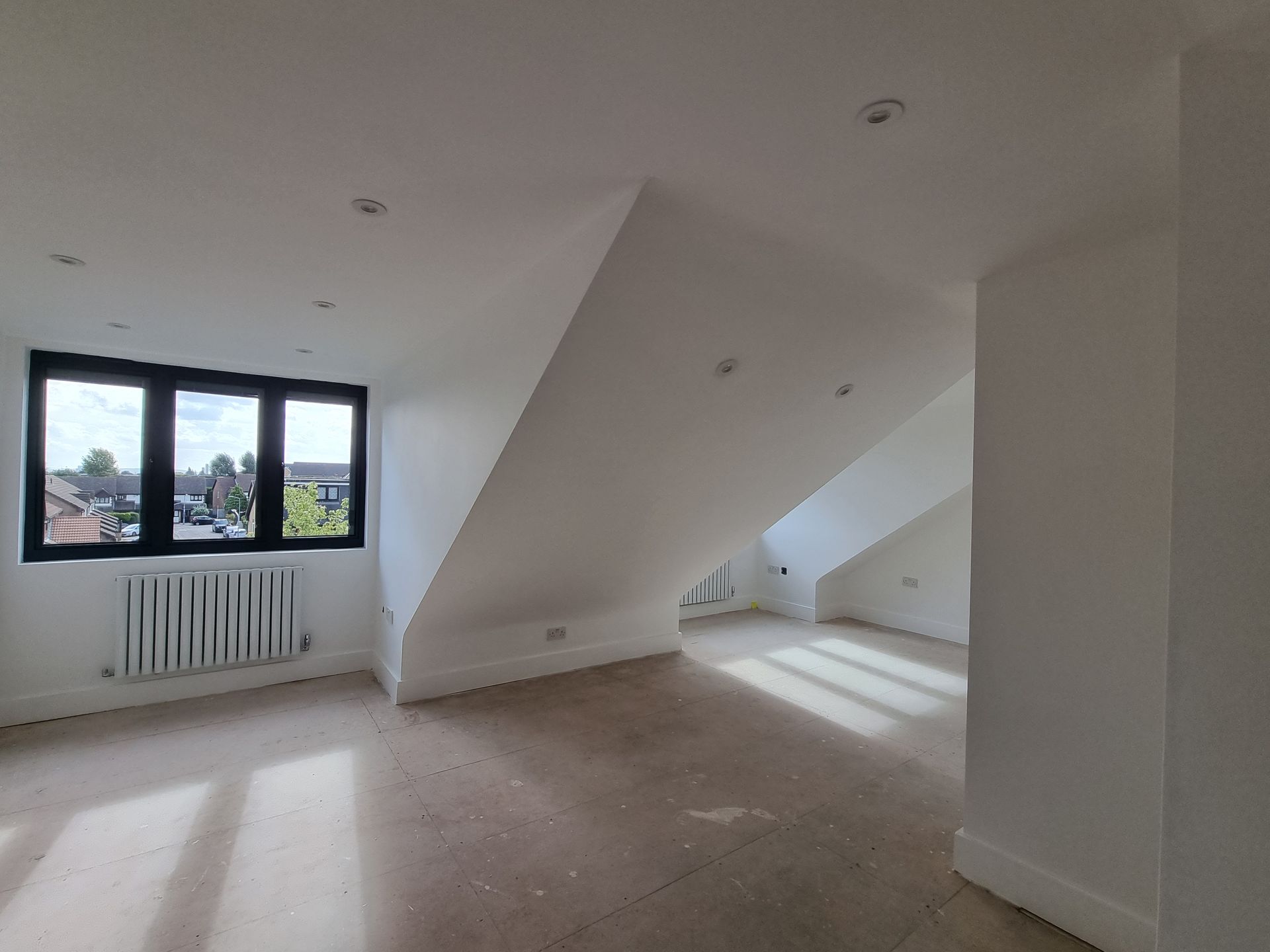 An empty room with a slanted ceiling and a window.