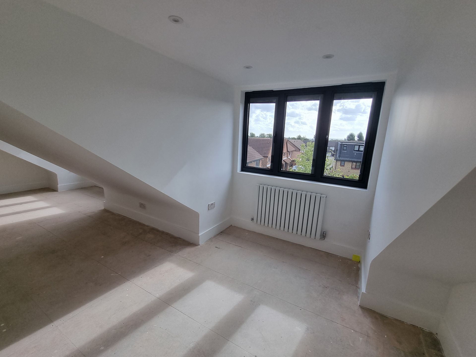An empty room with a window and a radiator.