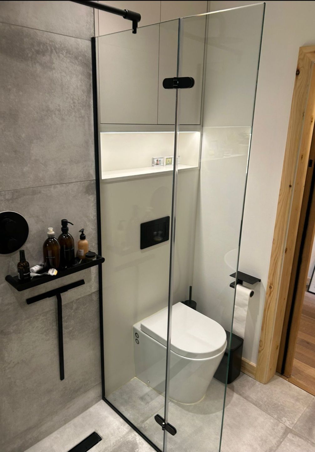 Modern bathroom with glass shower, toilet, and black fixtures.