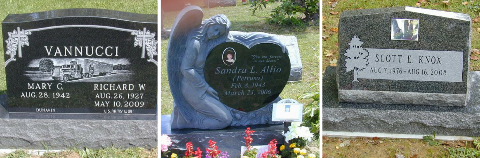 Three cemetery headstones, one dark and two light, with flowers at the base of the middle stone.