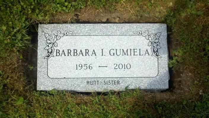Gravestone for Barbara L. Gumila, 1956–2010, set in grass with decorative border.