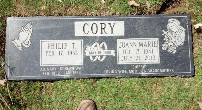 Gravestone for Cory with two name plaques and small angel carvings on a grassy cemetery plot.