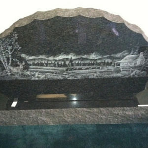 Black-and-white engraved mountain landscape on a plaque, with trees and a small cabin scene.