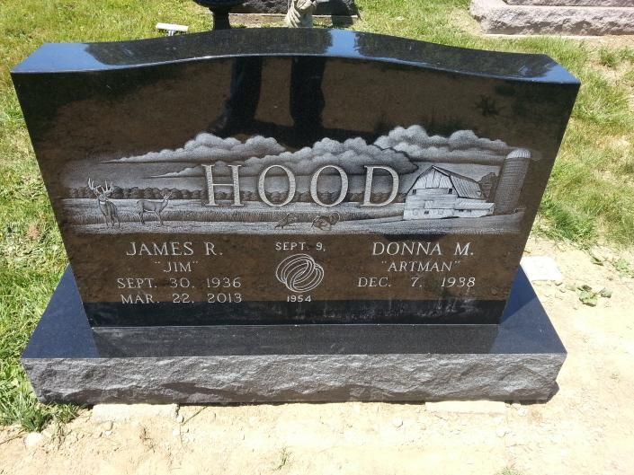 Black granite gravestone with the name Hood engraved in a grassy cemetery.