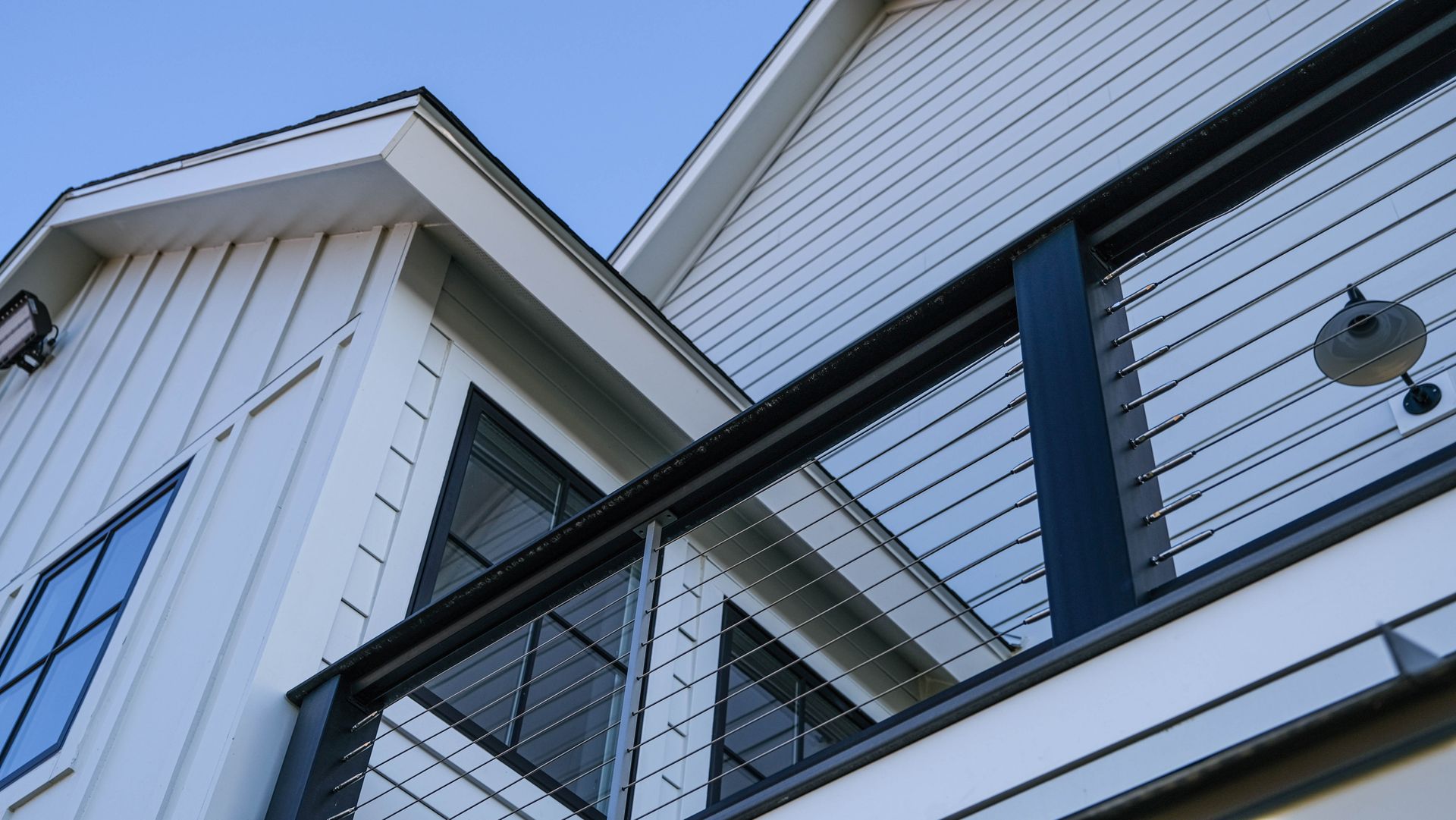Maison blanche avec une balustrade noire, ciel bleu.