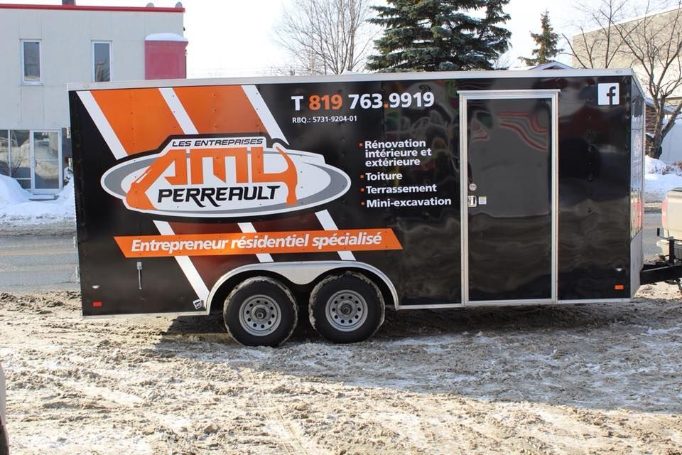 Une remorque noire et orange portant le logo « AML Perreault », un numéro de téléphone et la liste des services offerts est stationnée à l'extérieur, sur la neige.
