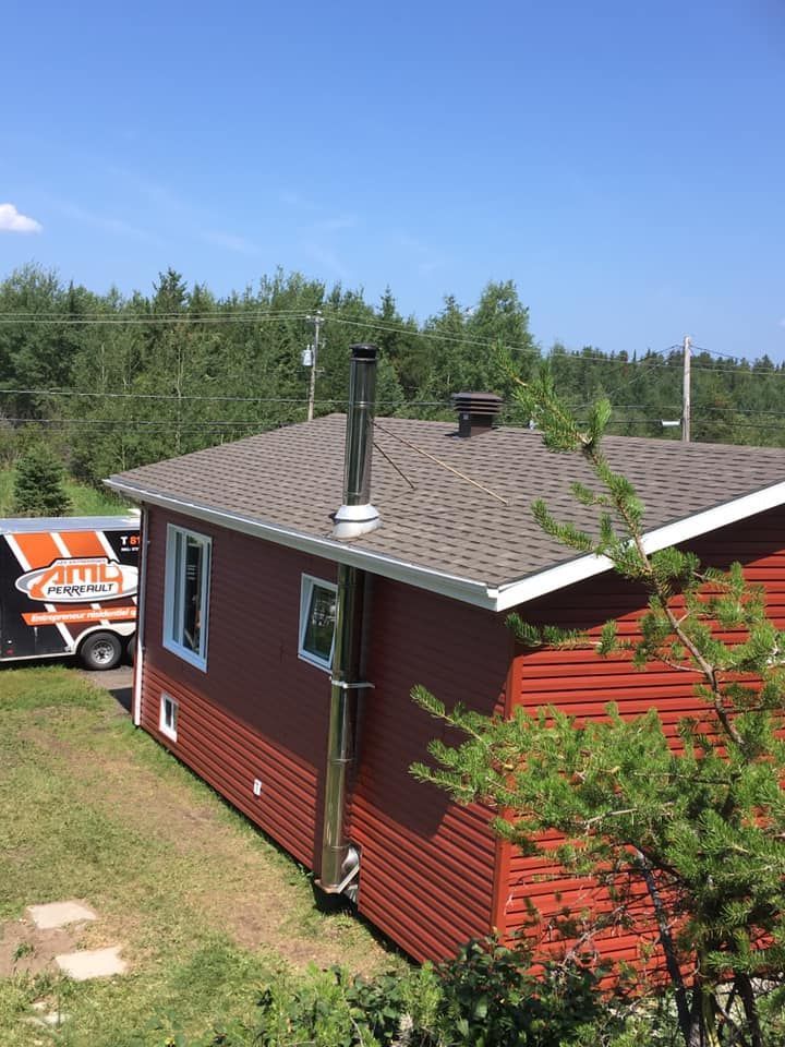 Cabane rouge avec cheminée en acier inoxydable par une journée ensoleillée.