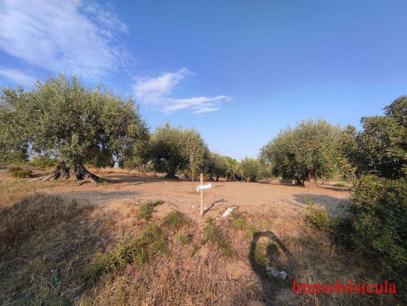 Caletta sabbiosa con acqua turchese, scogliere rocciose e un cielo azzurro limpido.