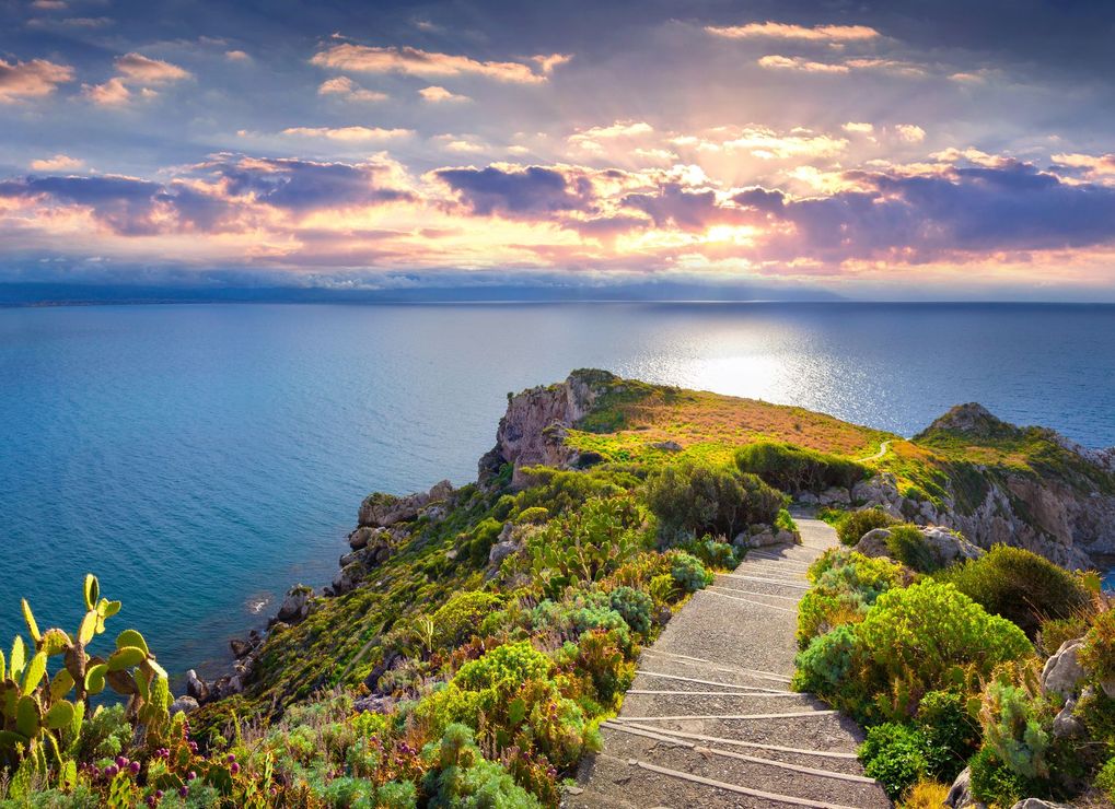 Caletta sabbiosa con acqua turchese, scogliere rocciose e un cielo azzurro limpido.