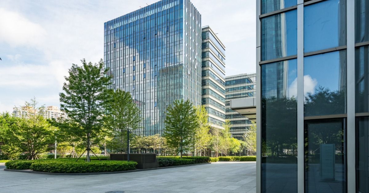 There are several buildings in a corporate park. There is a park with trees in a courtyard area.