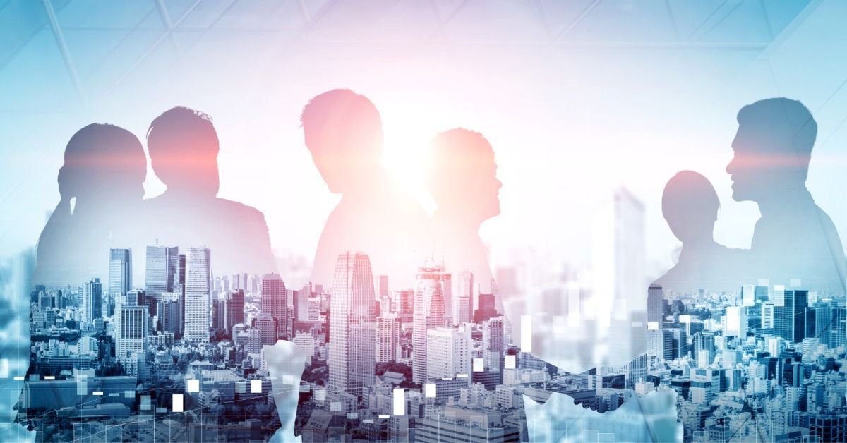 A group of people in silhouette are standing in a group.