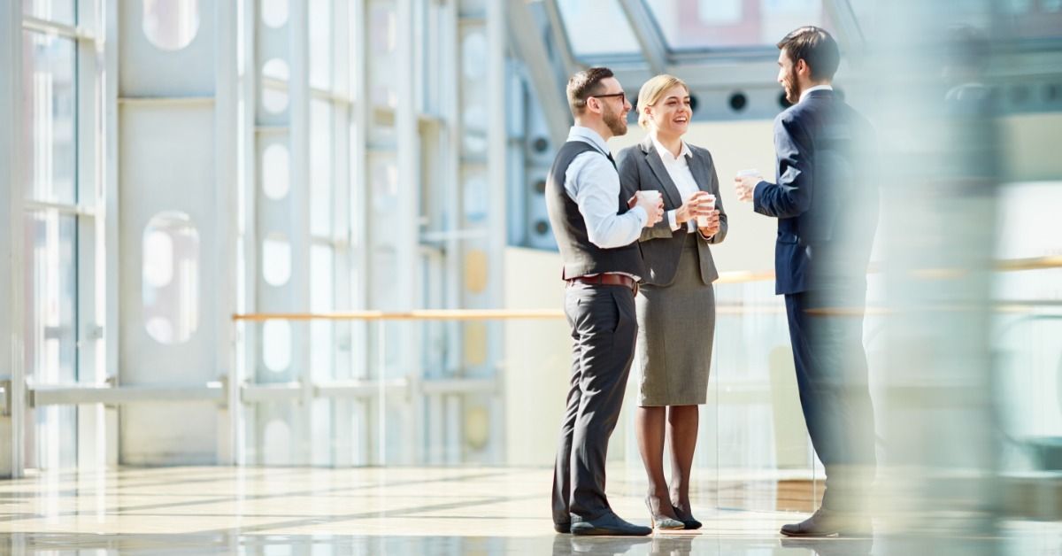 Several people are standing together; they are all wearing business attire. They are in a lobby area.