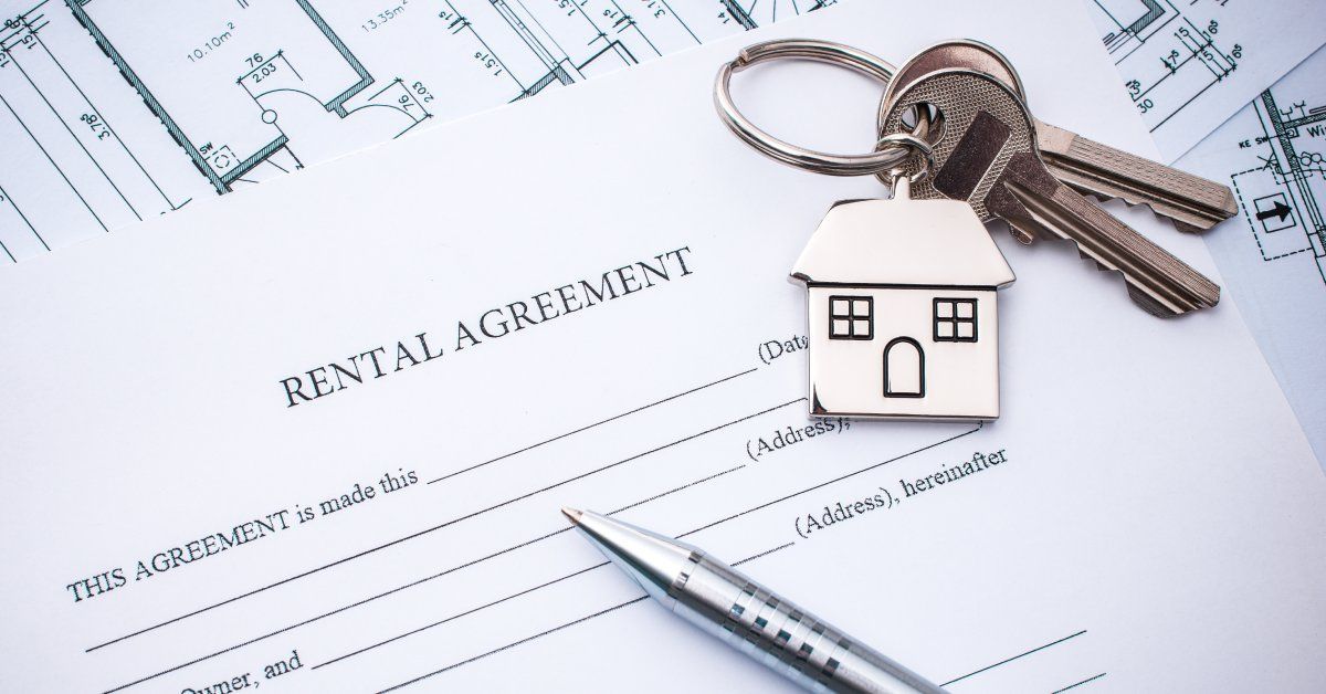Closeup of a document lying on a table that says “Rental Agreement” at the top next to a pen and a set of keys.