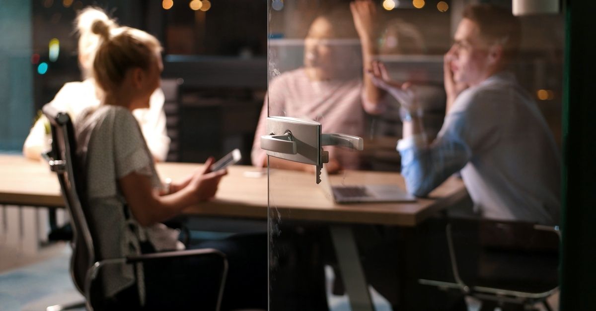 Several people are sitting at a table. There is a pane of glass between the camera and the people.